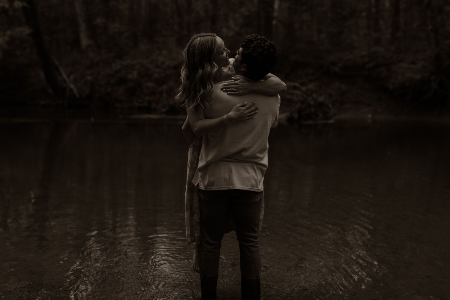 A romantic couple shares a tender moment together in an outdoor setting at sunset.