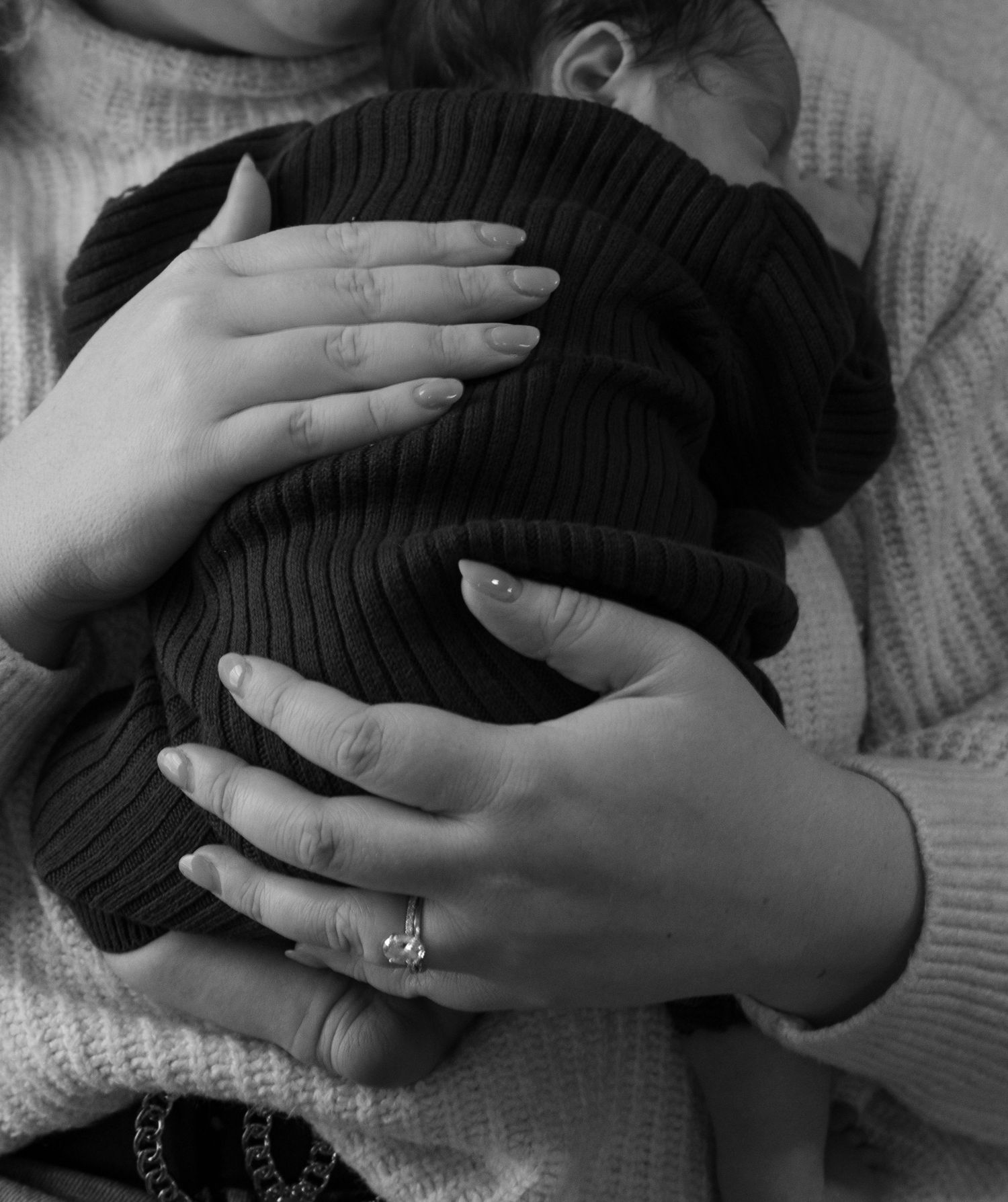 Hands tenderly caressing a head against a soft knitted sweater background.