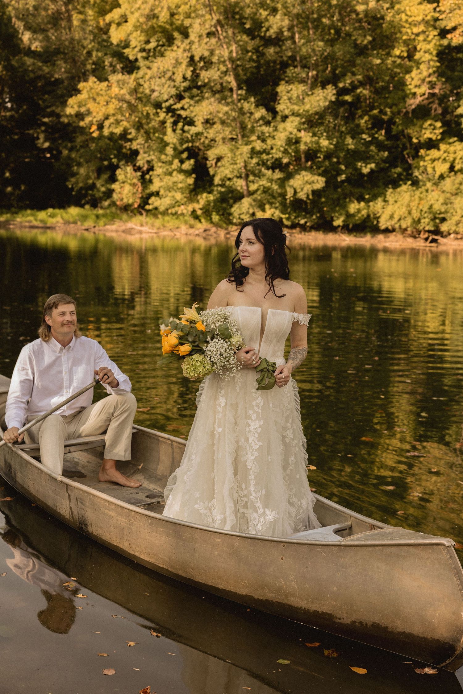 A romantic canoe engagement session on a lake surrounded by golden autumn foliage.
