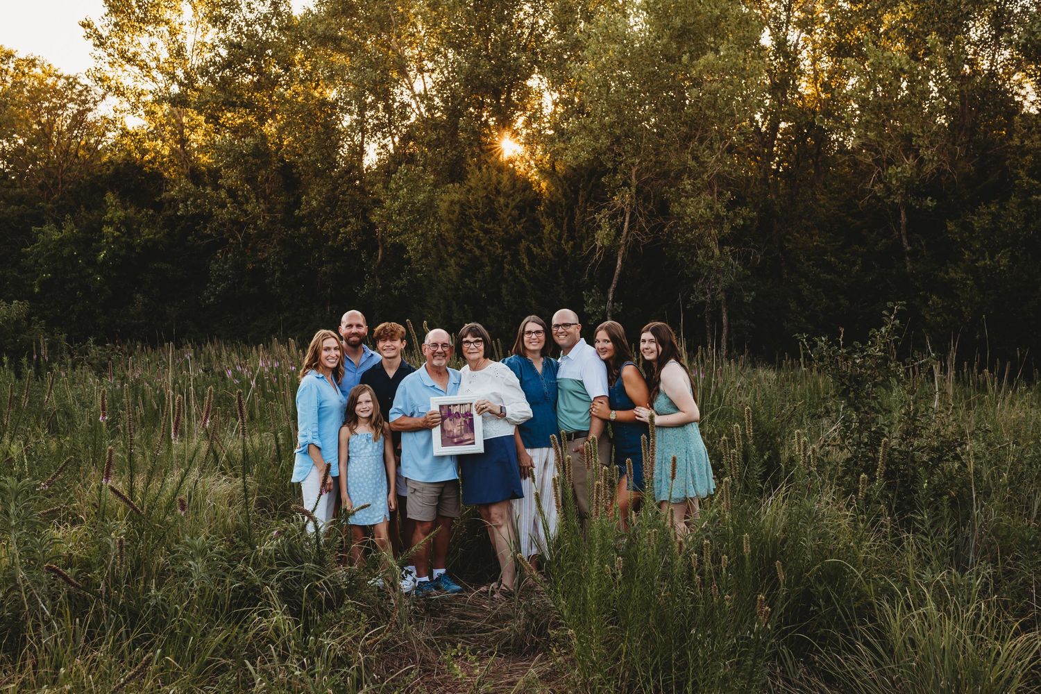 Extended family gathering in a green meadow at golden hour.