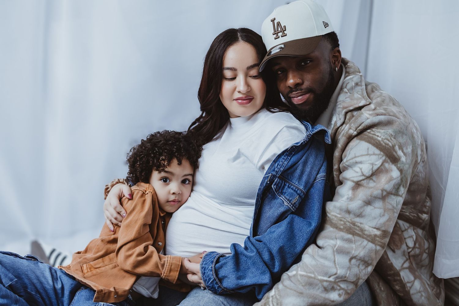 Military father, pregnant mother, and young son posing together for maternity family portrait.