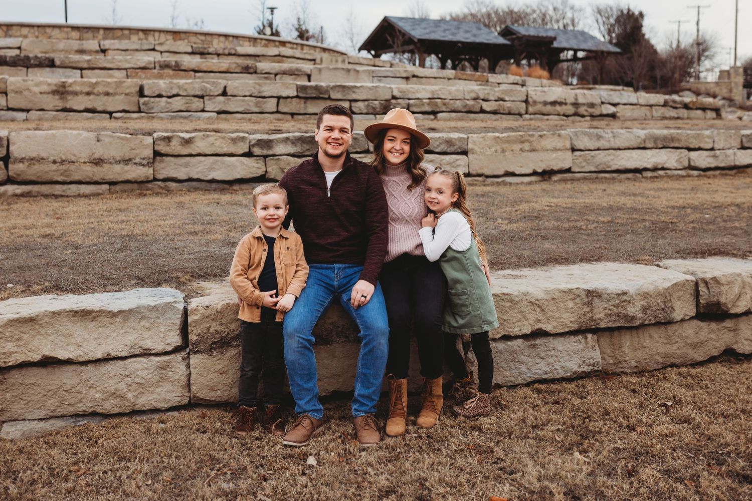 Family of four smiling together on stone steps outdoors.