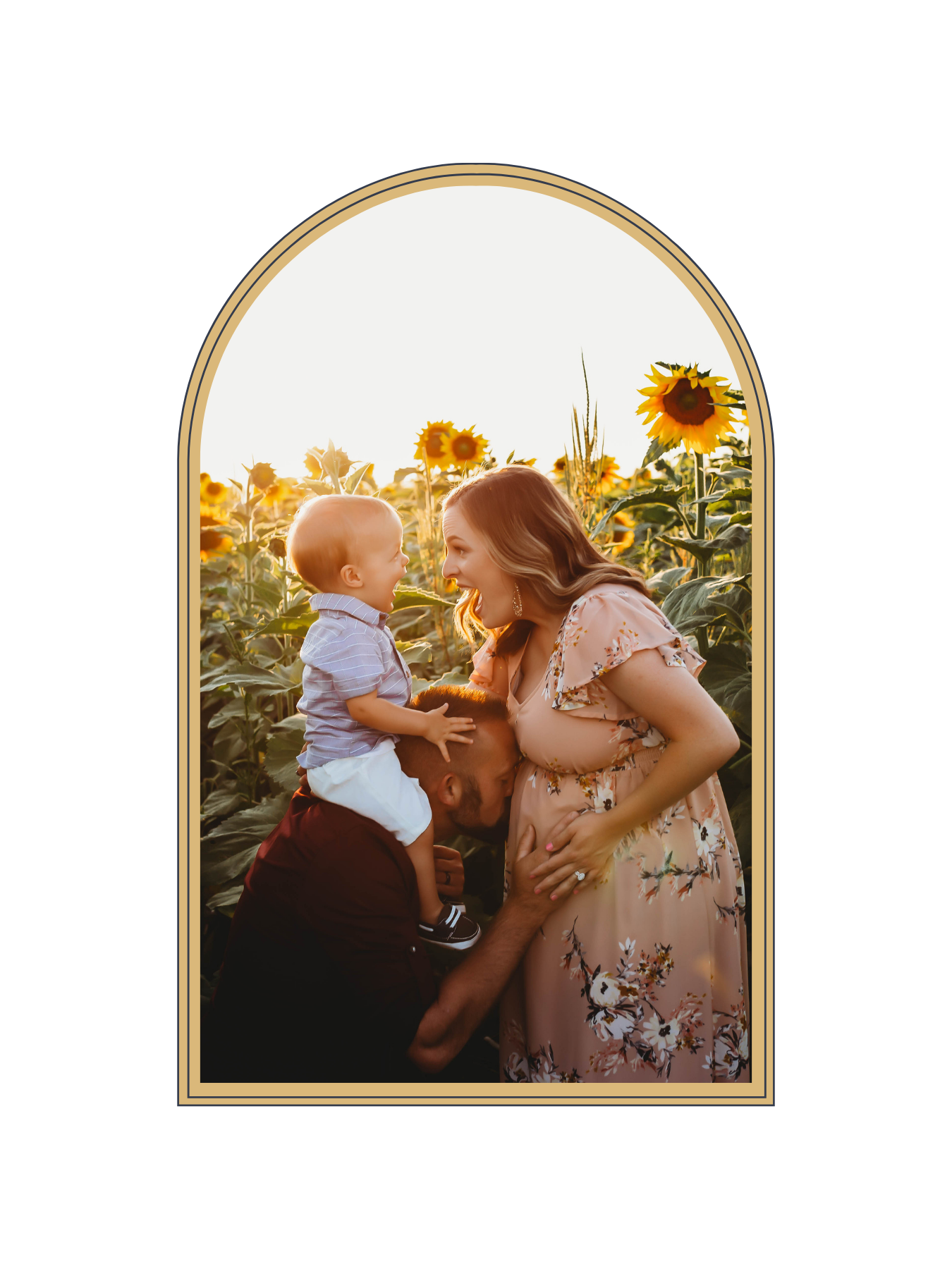 Pregnant woman in floral dress holding baby boy in a sunflower field, framed in gold arch.
