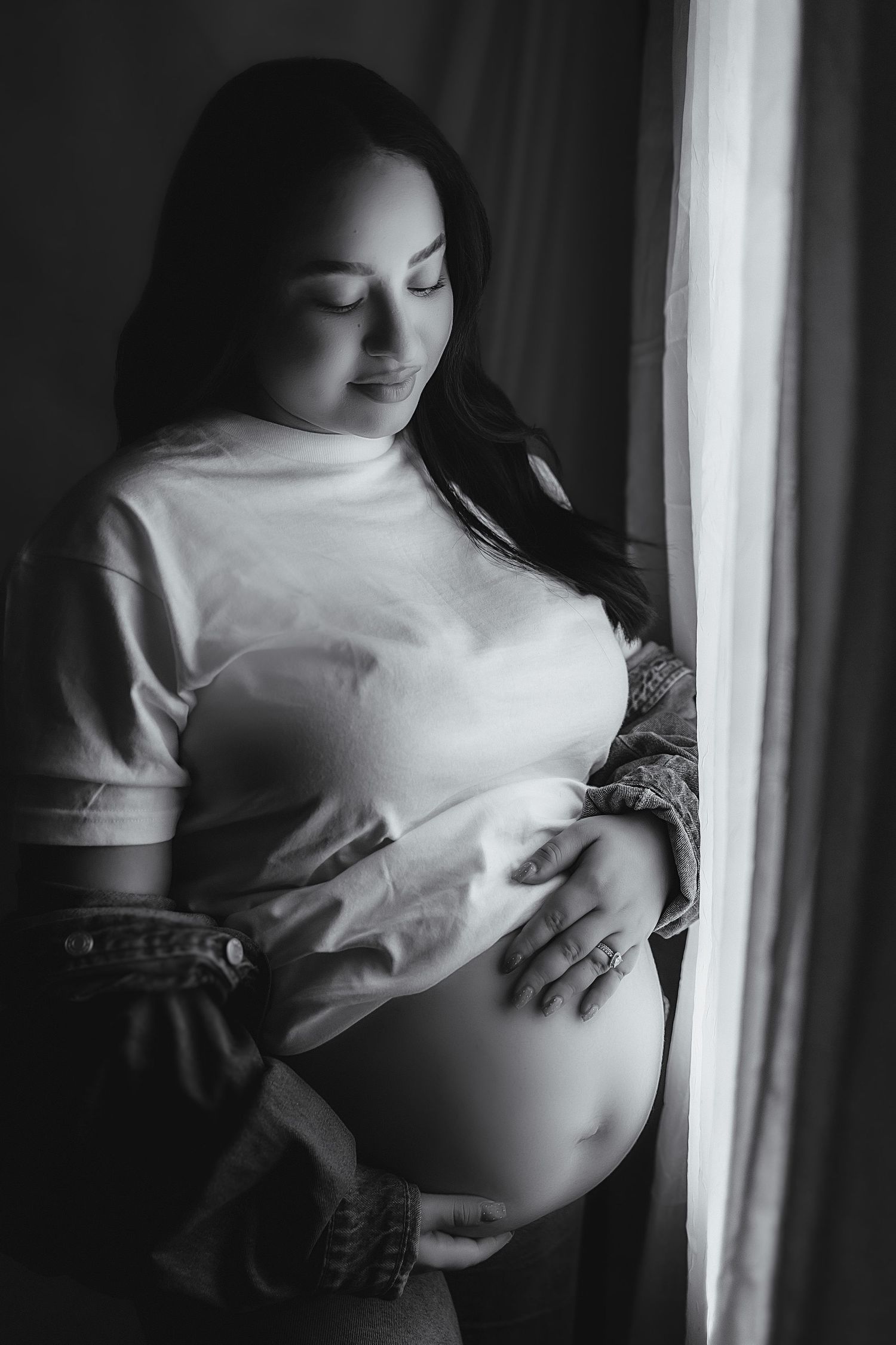 Moody maternity photo with natural light at an indoor studio.