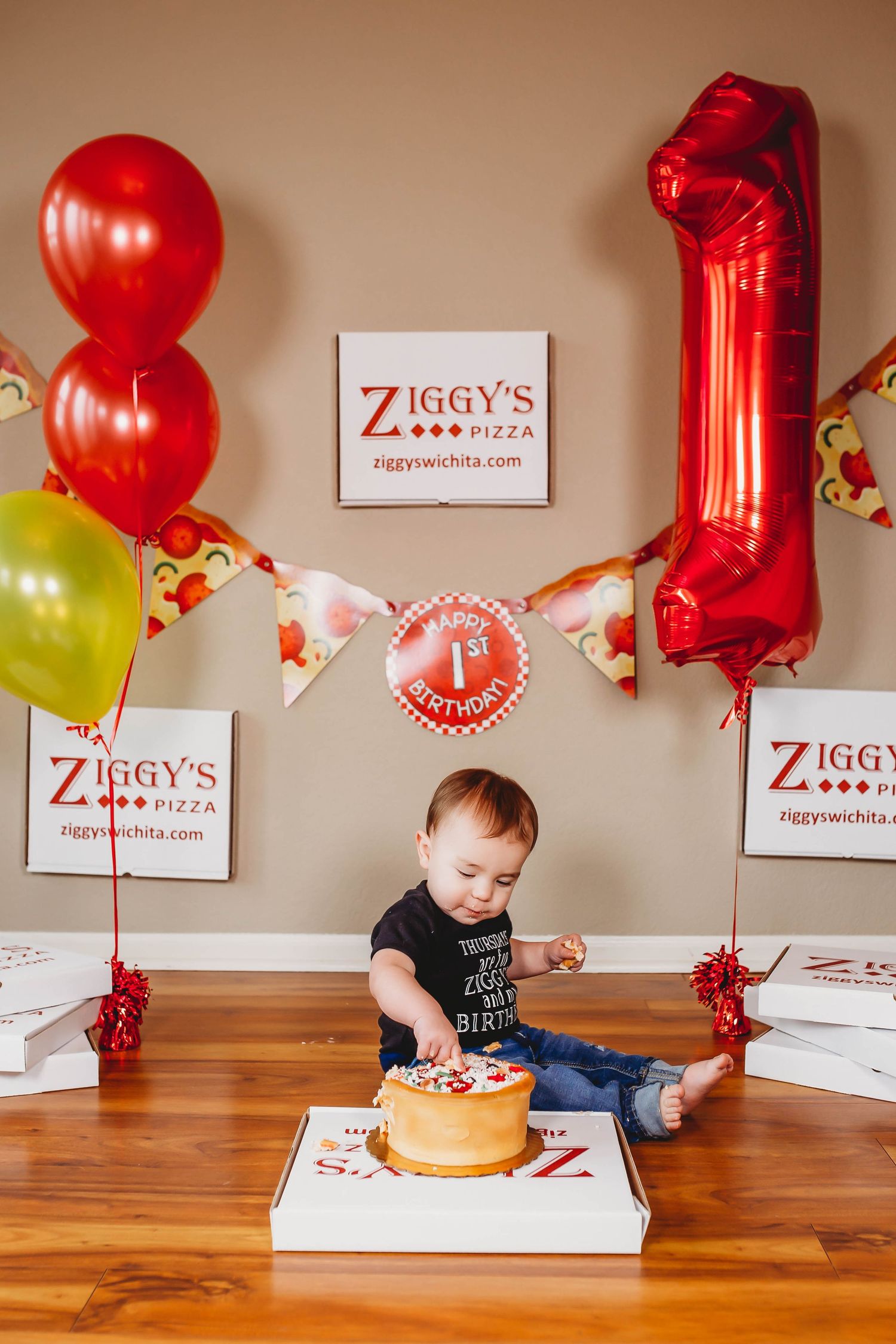 Baby celebrating first birthday with cake at Ziggy's Pizza party.