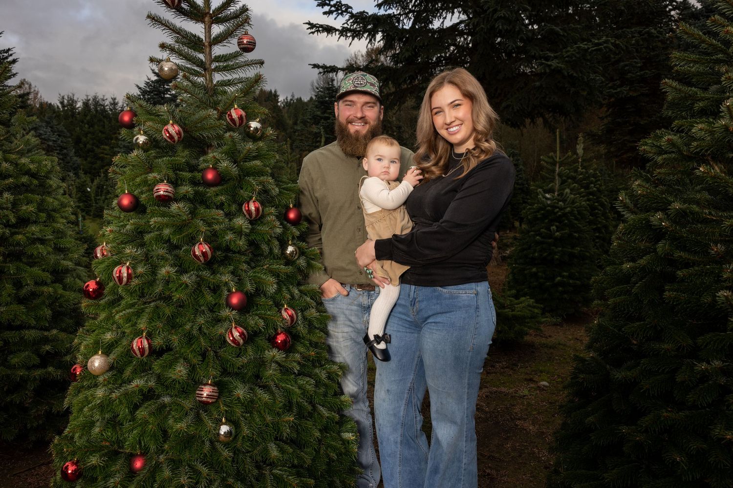 Casual family portraits in front of decorated evergreen Christmas tree.