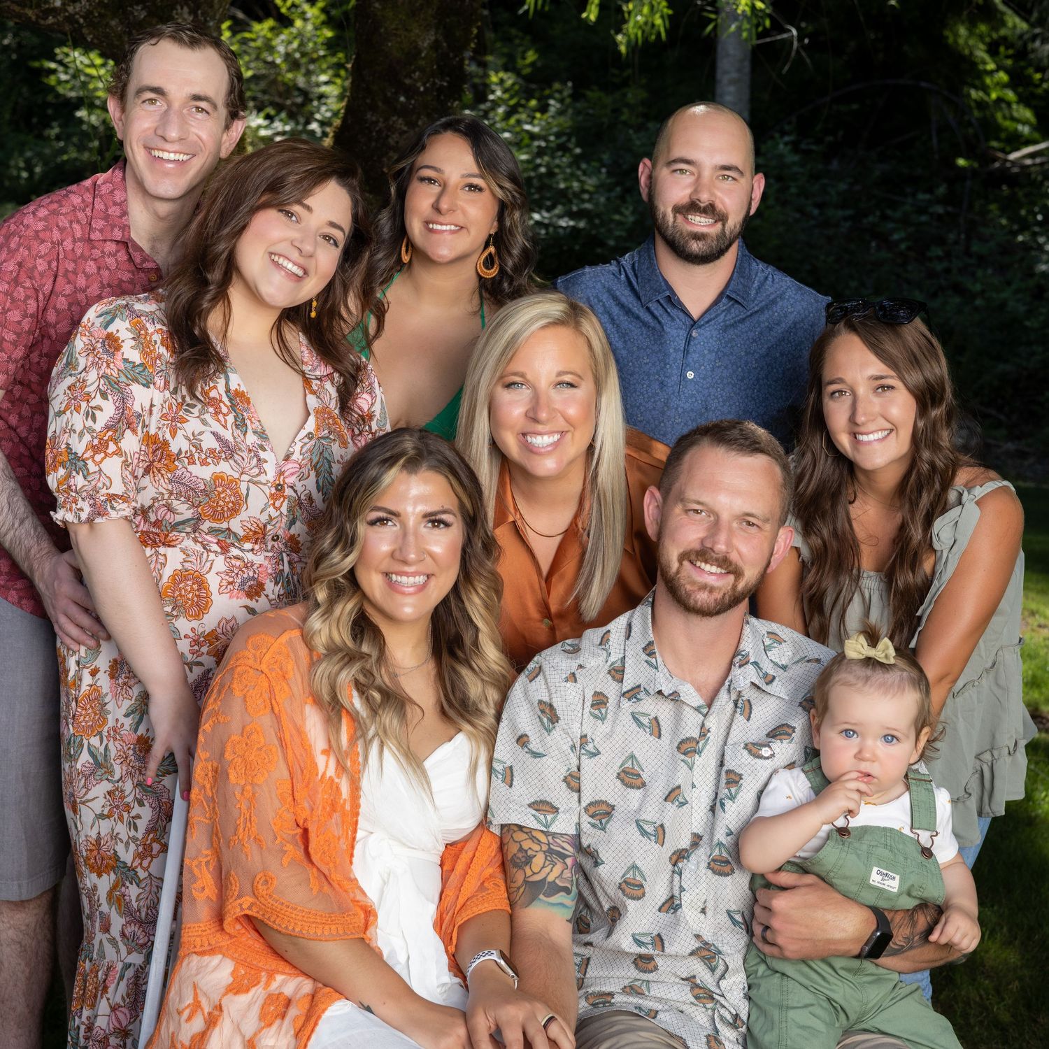 Large family group in coordinated outfits poses together for outdoor portrait.