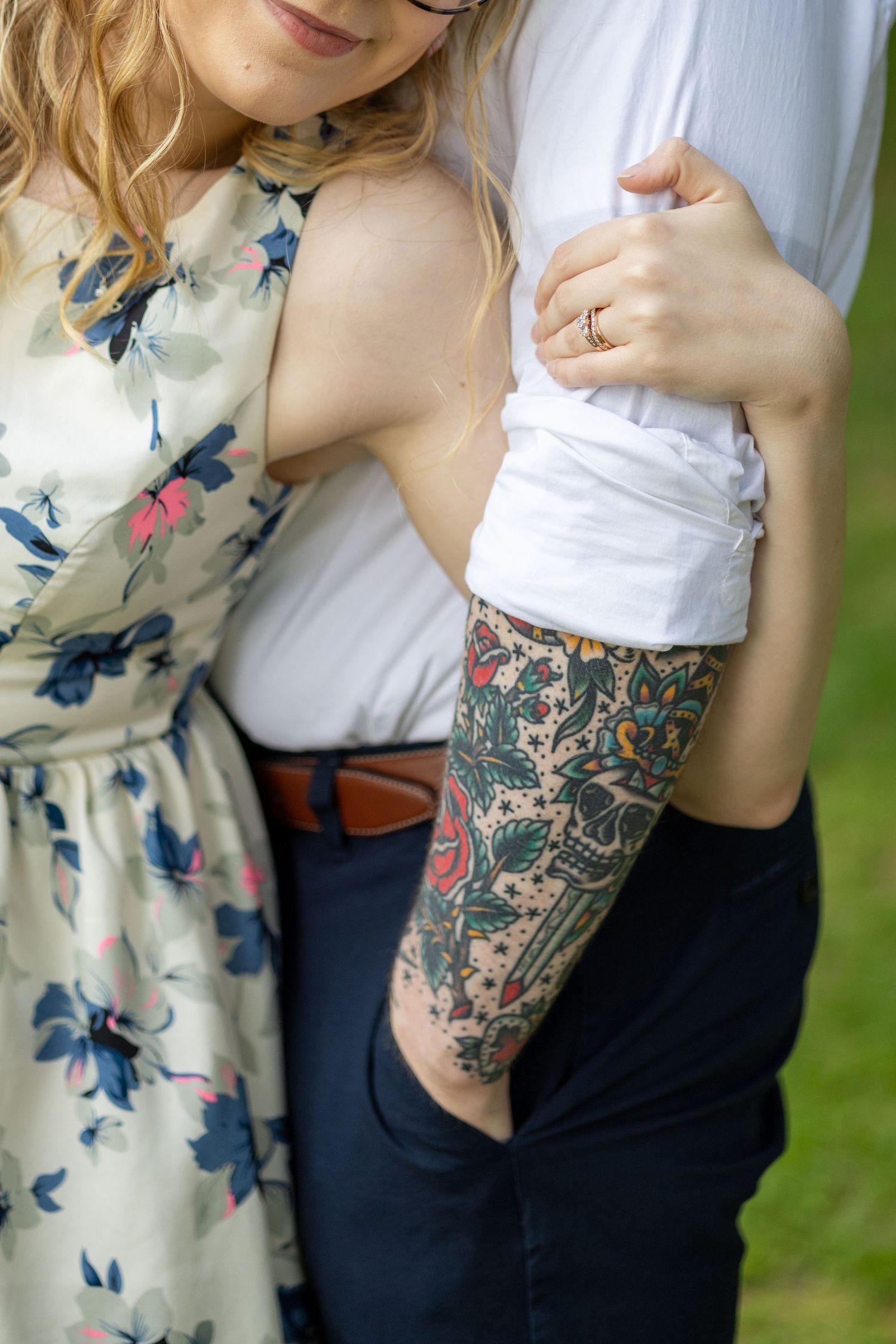 Close-up details of a couple in floral dress and white shirt showing tattoo sleeve artwork.
