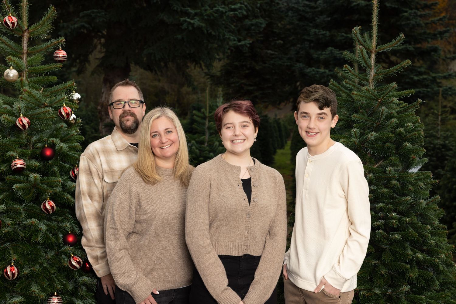 Family group photos in coordinated beige and white outfits against evergreen trees.