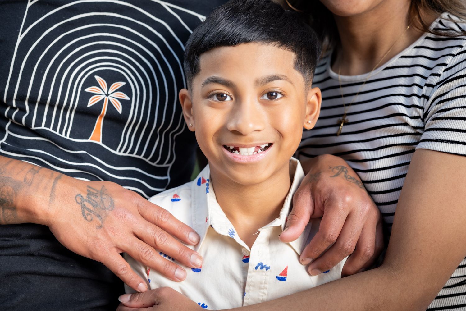Casual family portrait session with striped shirts against a dark background.