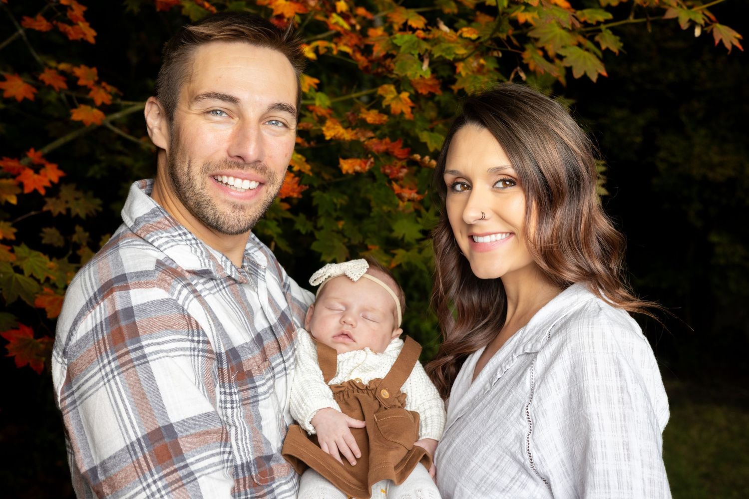 Family portrait session in autumn with colorful fall foliage in the background.