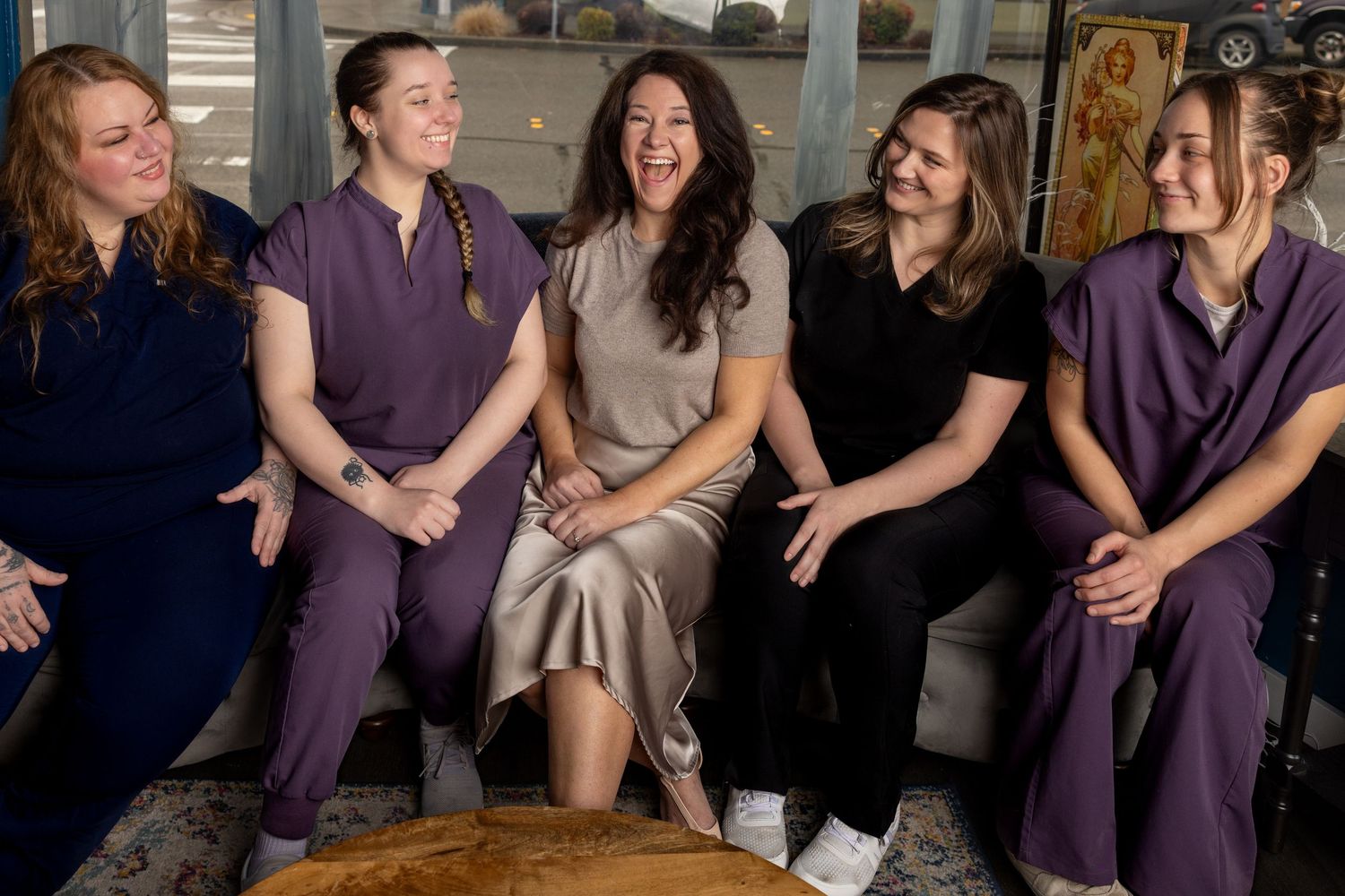 Group wearing purple outfits sitting together on a couch sharing laughs.