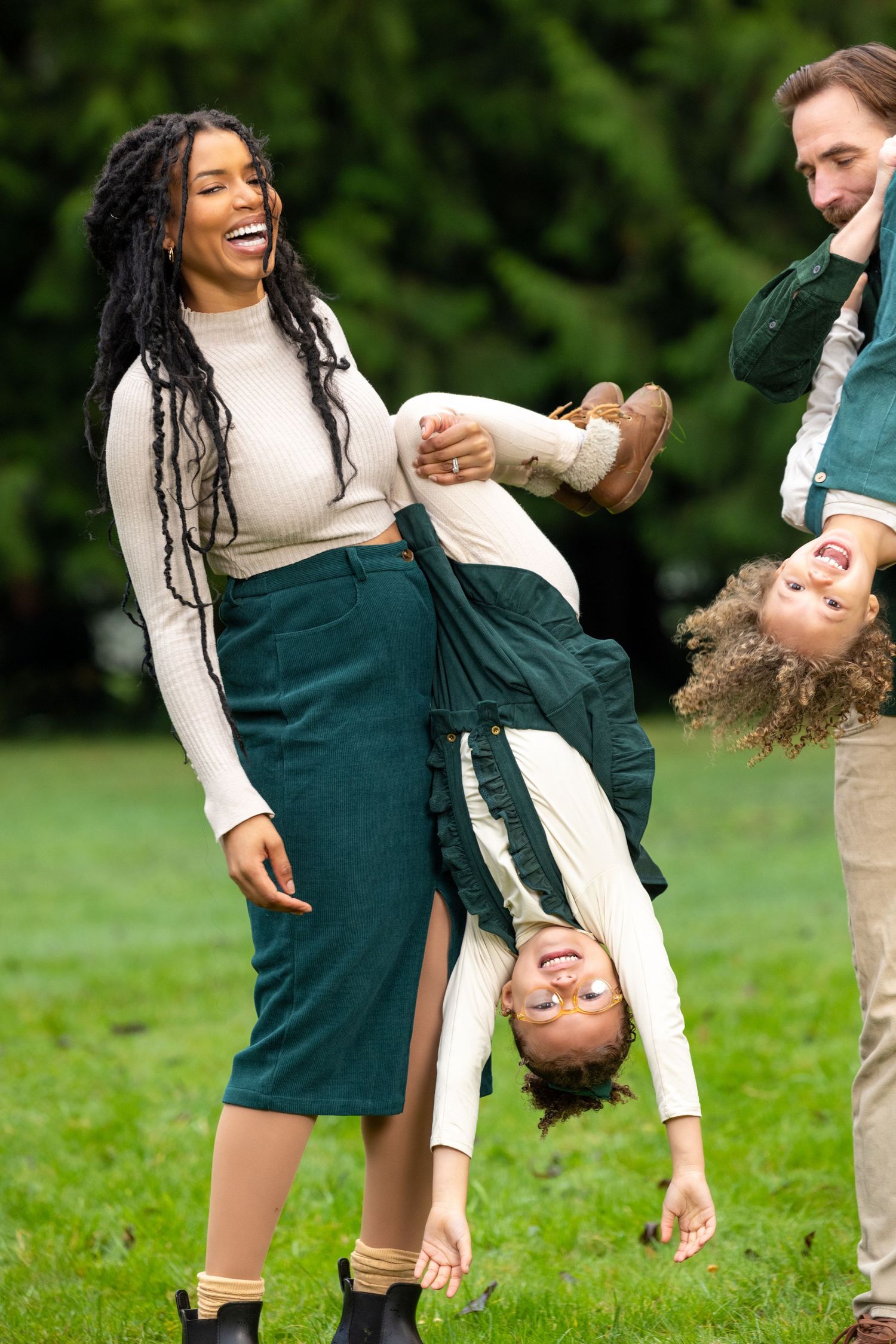 Playful couple shares dynamic moments in a grassy field during a photo session.