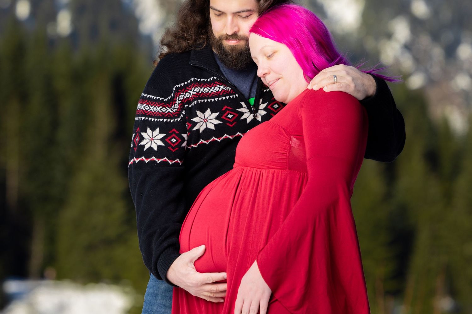 Winter portrait session with snowy mountains and evergreen trees in the background.