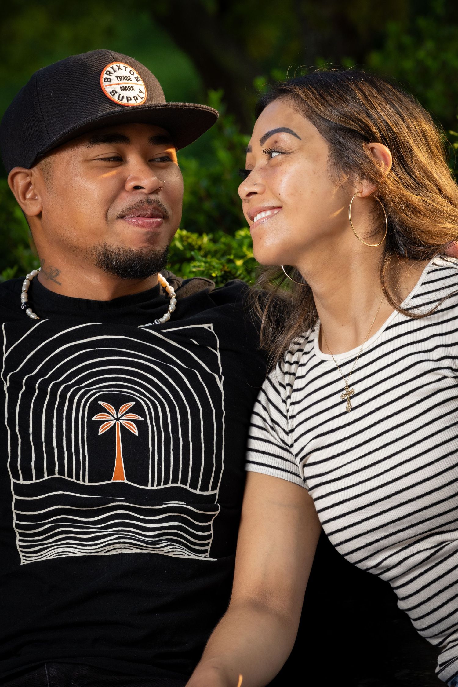 A couple wearing black and striped shirts pose together in a series of romantic outdoor photos.