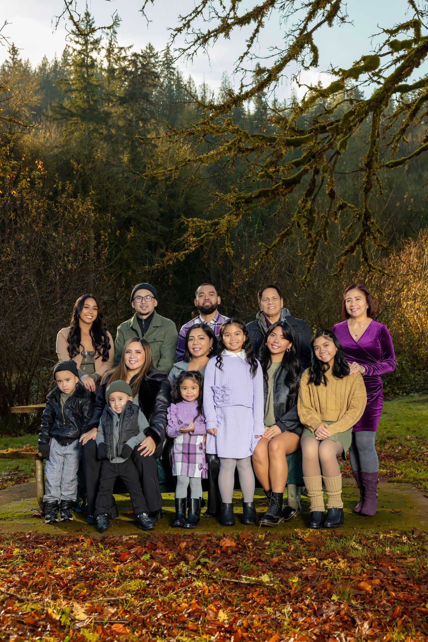 Group photo of people sitting together on fallen autumn leaves in a forest setting.