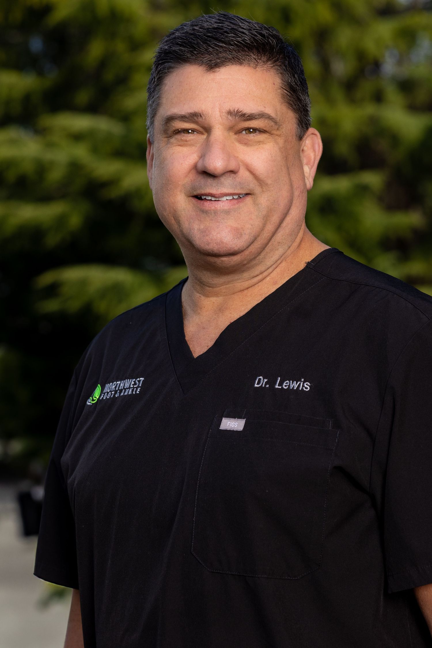 Medical professional in black scrubs standing outdoors.