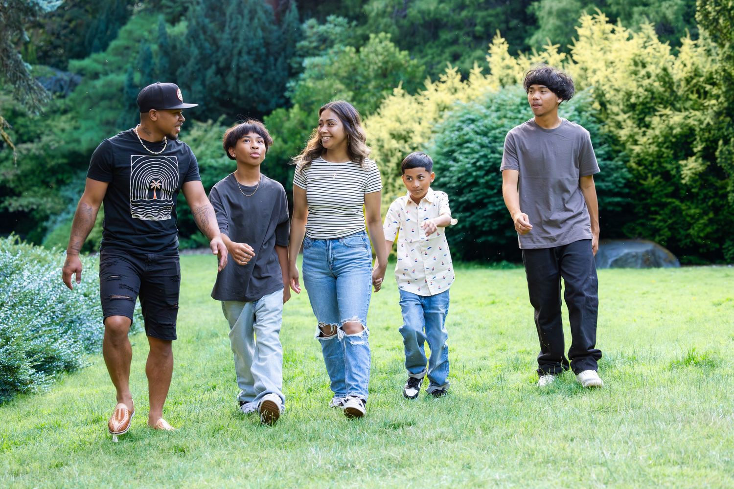 Group of people walking together on a grassy hill in a park during a sunny summer day.
