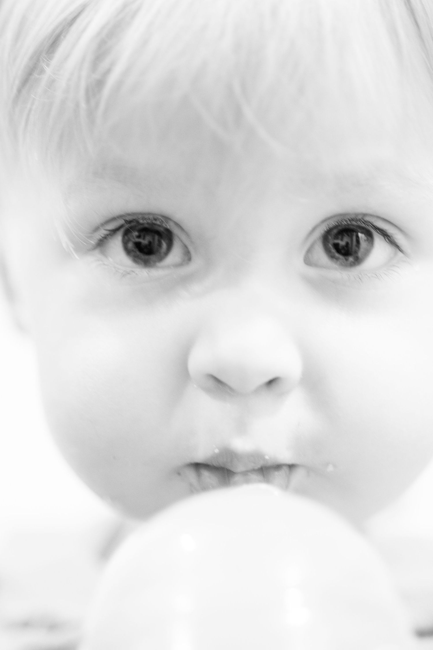 Close up black and white portrait of bright-eyed young child looking directly at camera.