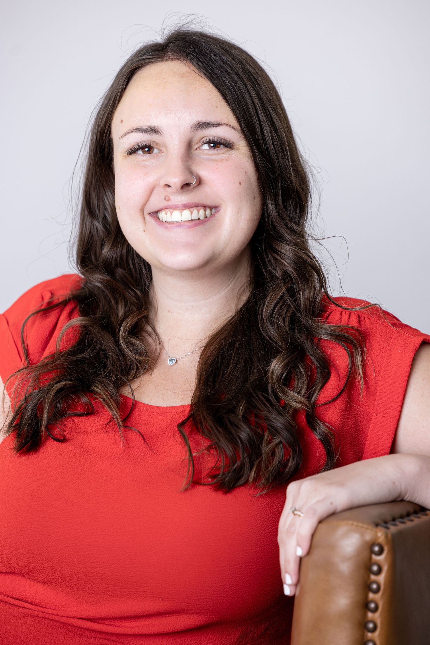 Professional headshot series showing bright smile and red top against light background.