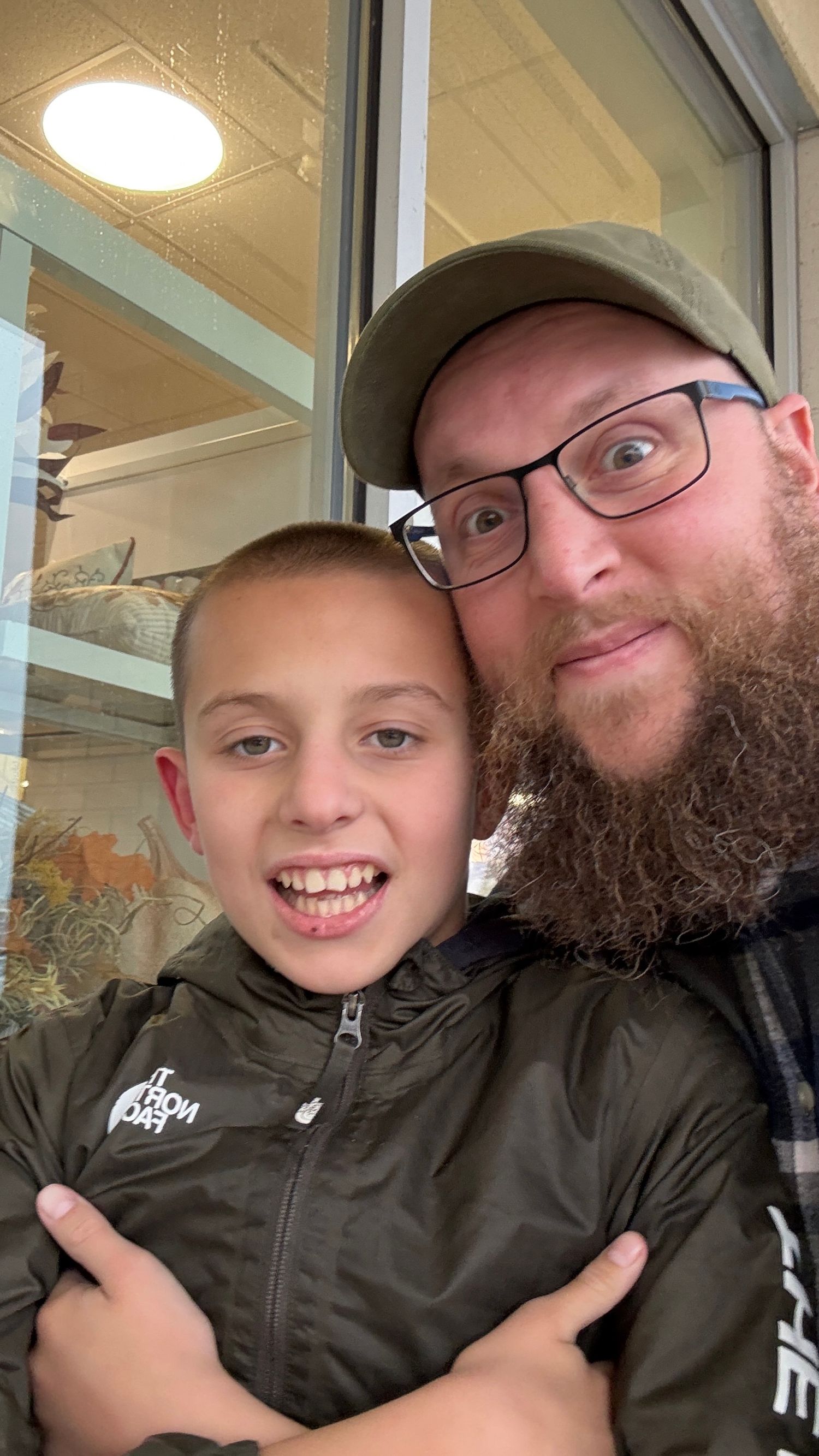 Close-up selfie showing two people smiling inside a building.