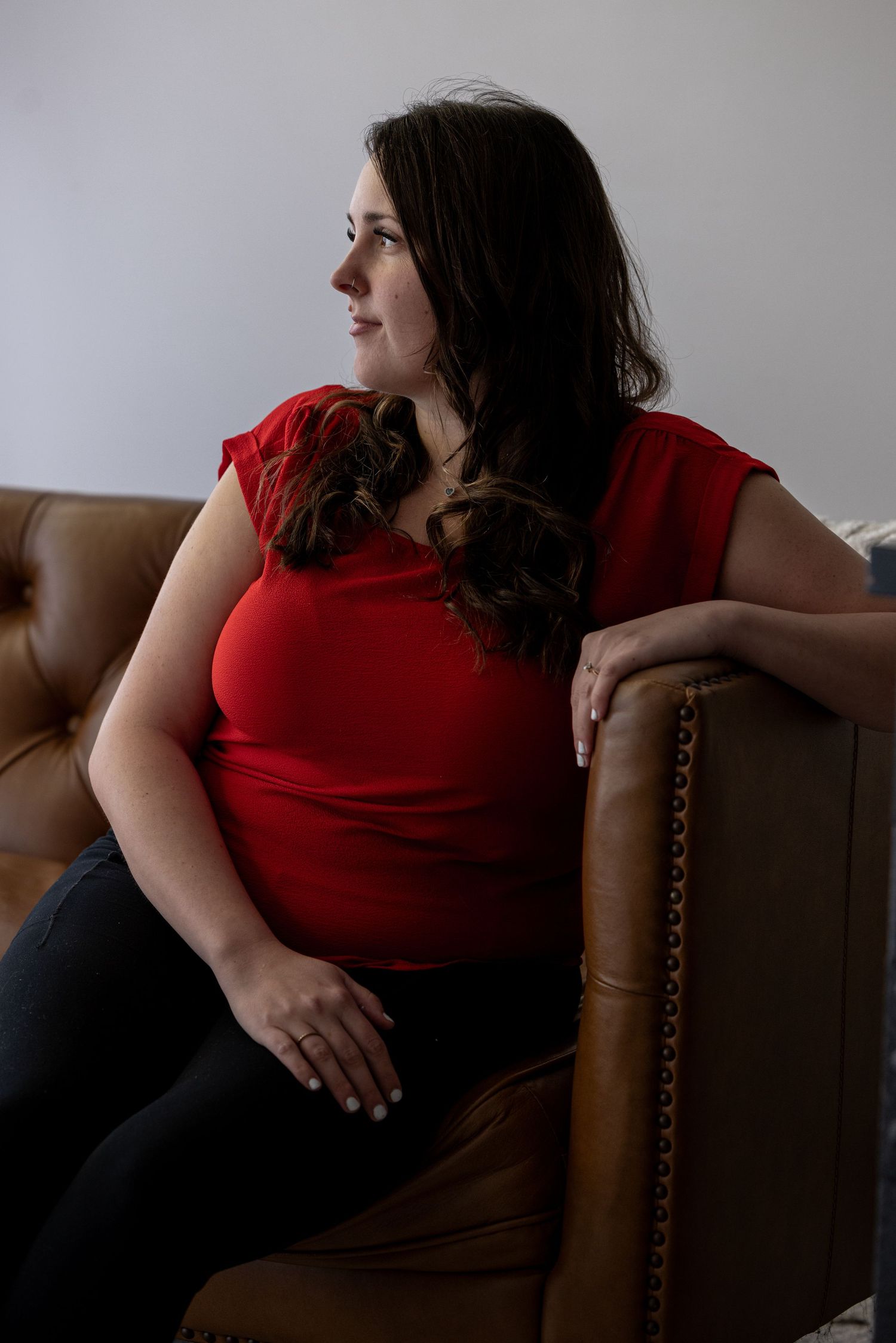 Person in red shirt relaxing on brown leather chair in casual poses.