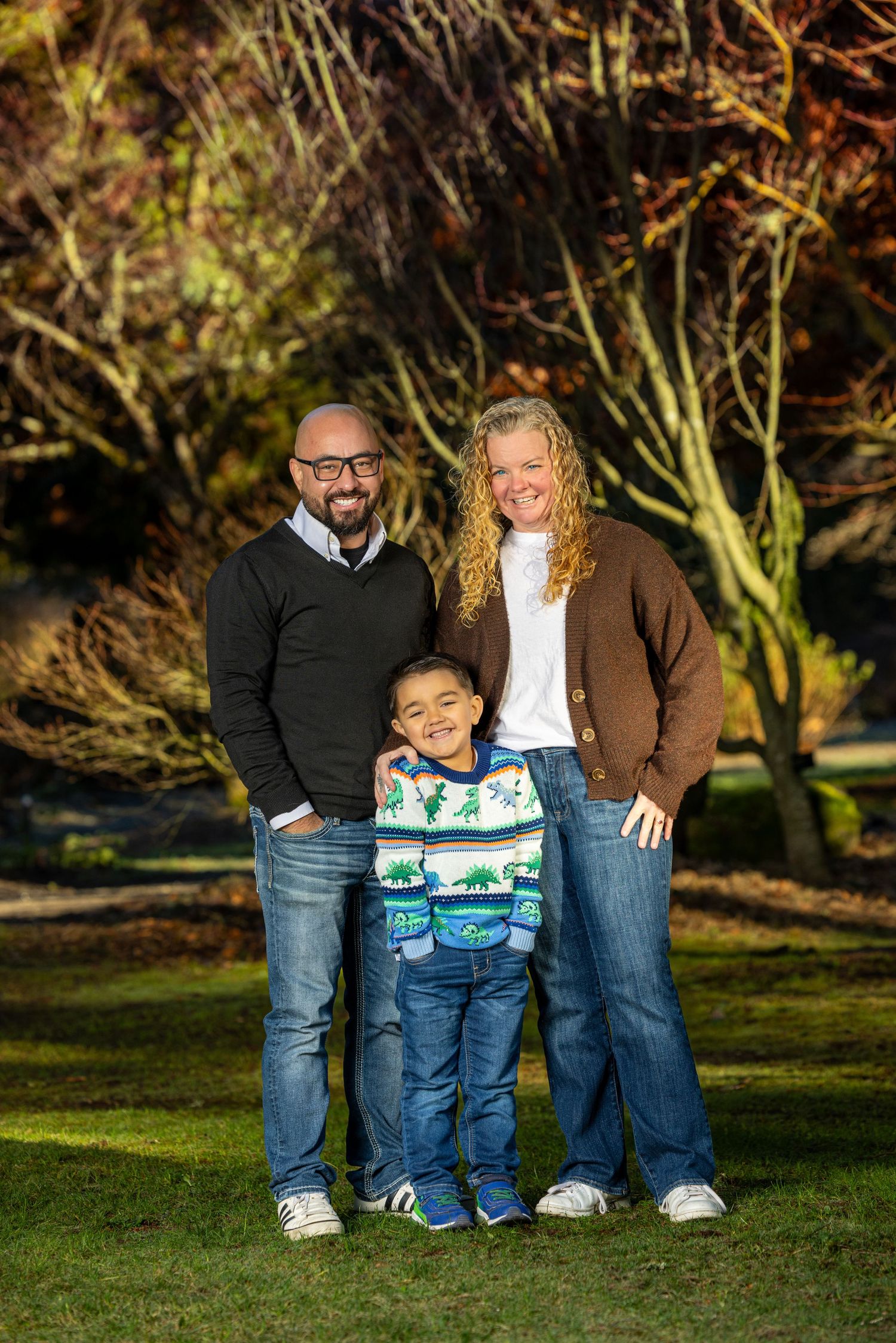 Family portrait session in a park with autumn foliage in the background.