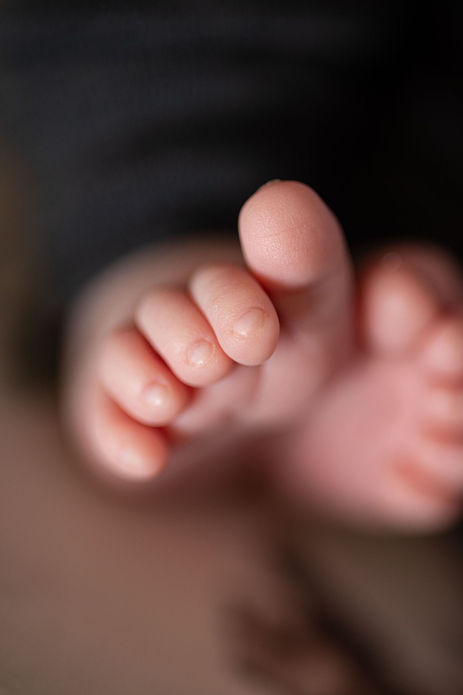 Close-up macro shot of tiny baby toes against dark background.