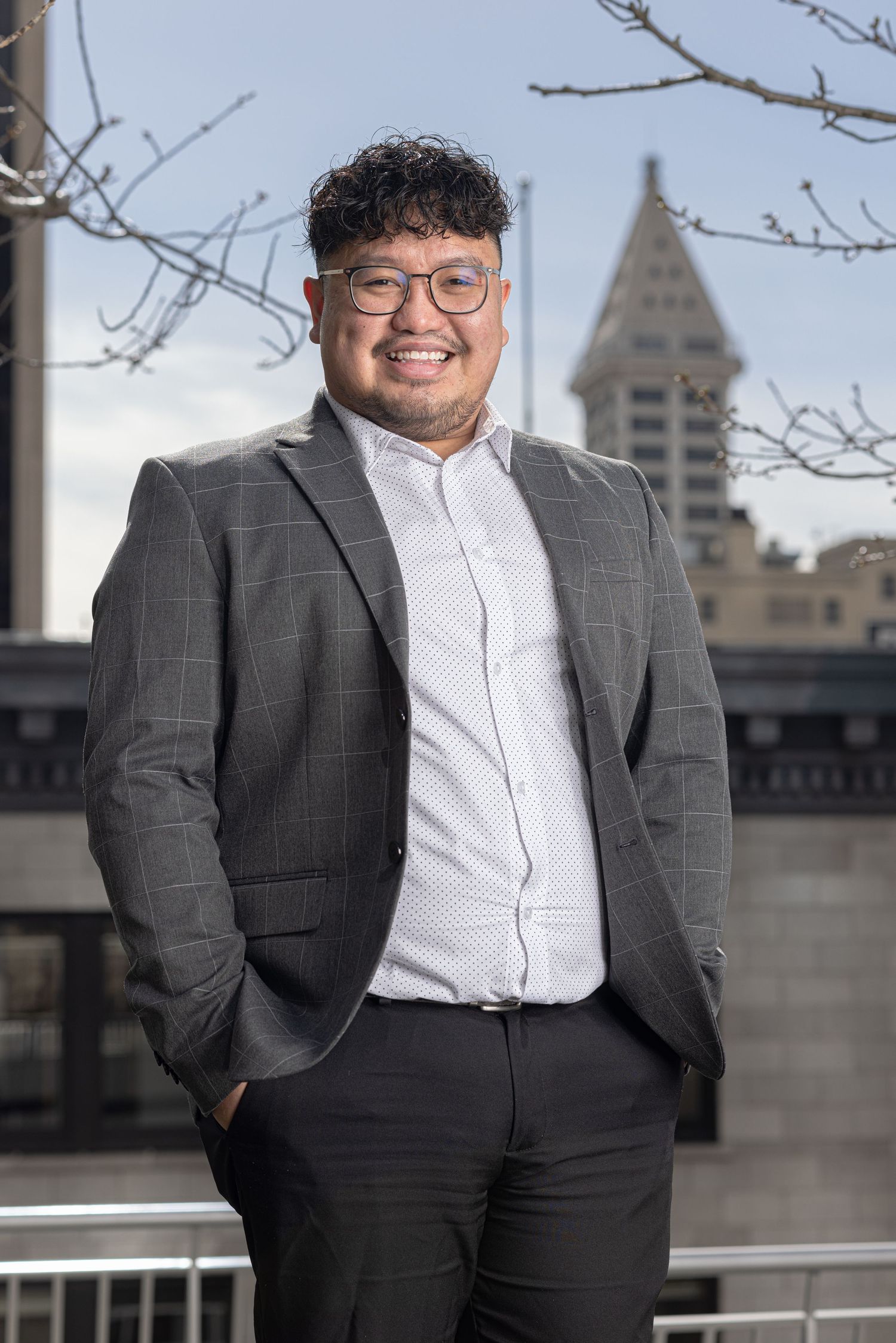 Professional outdoor portraits in grey suit with city architecture in background.