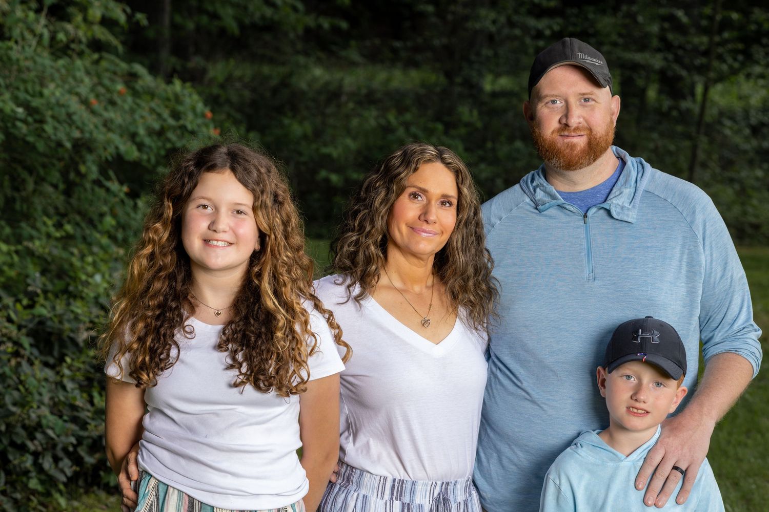Family portrait session outdoors with everyone wearing coordinated white outfits.