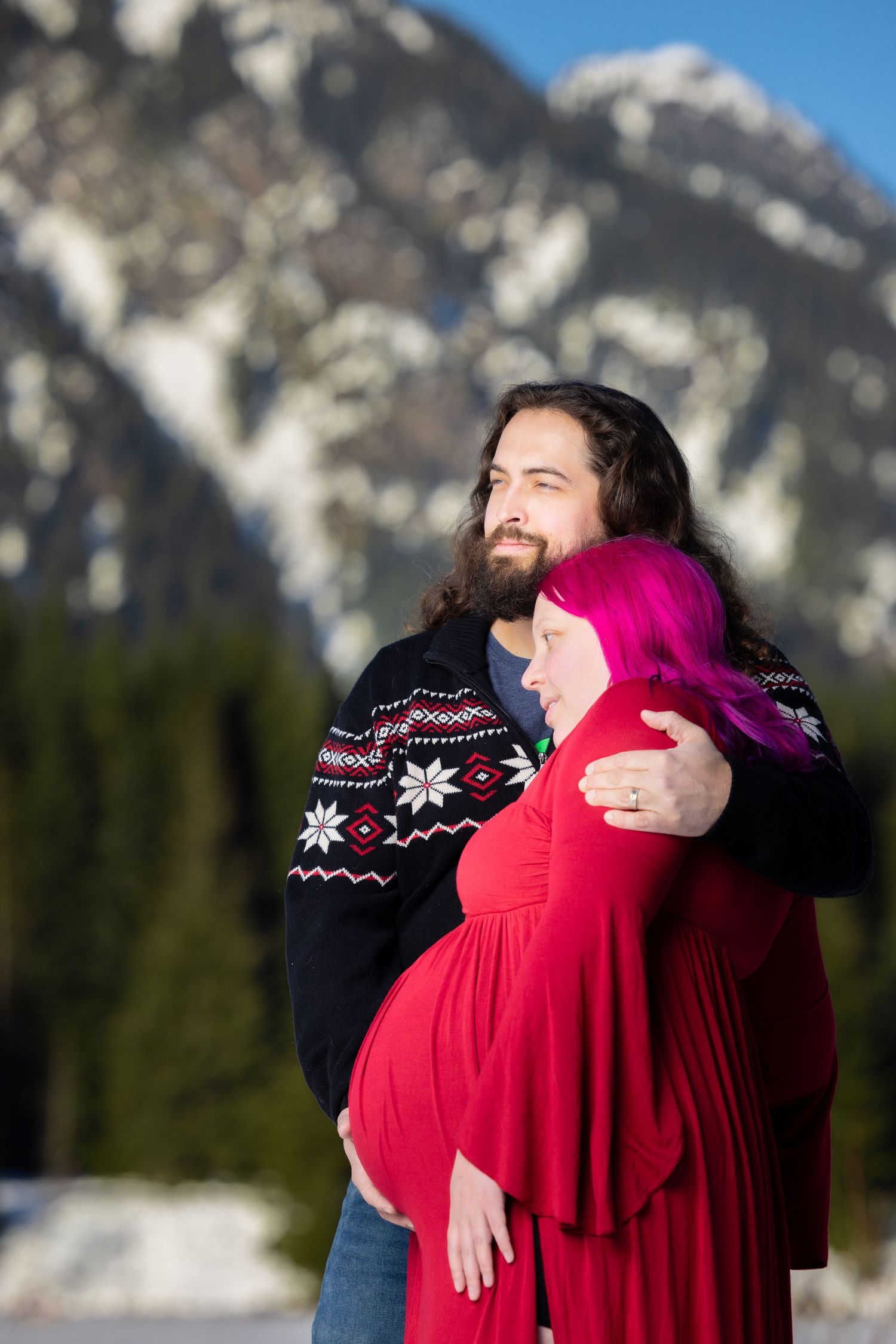 Winter maternity photo shoot with snowy mountain backdrop.