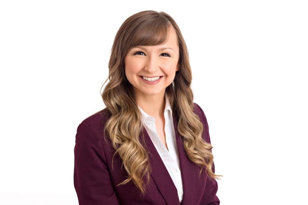 Professional woman in burgundy blazer smiling confidently against white background, corporate headshot photo.