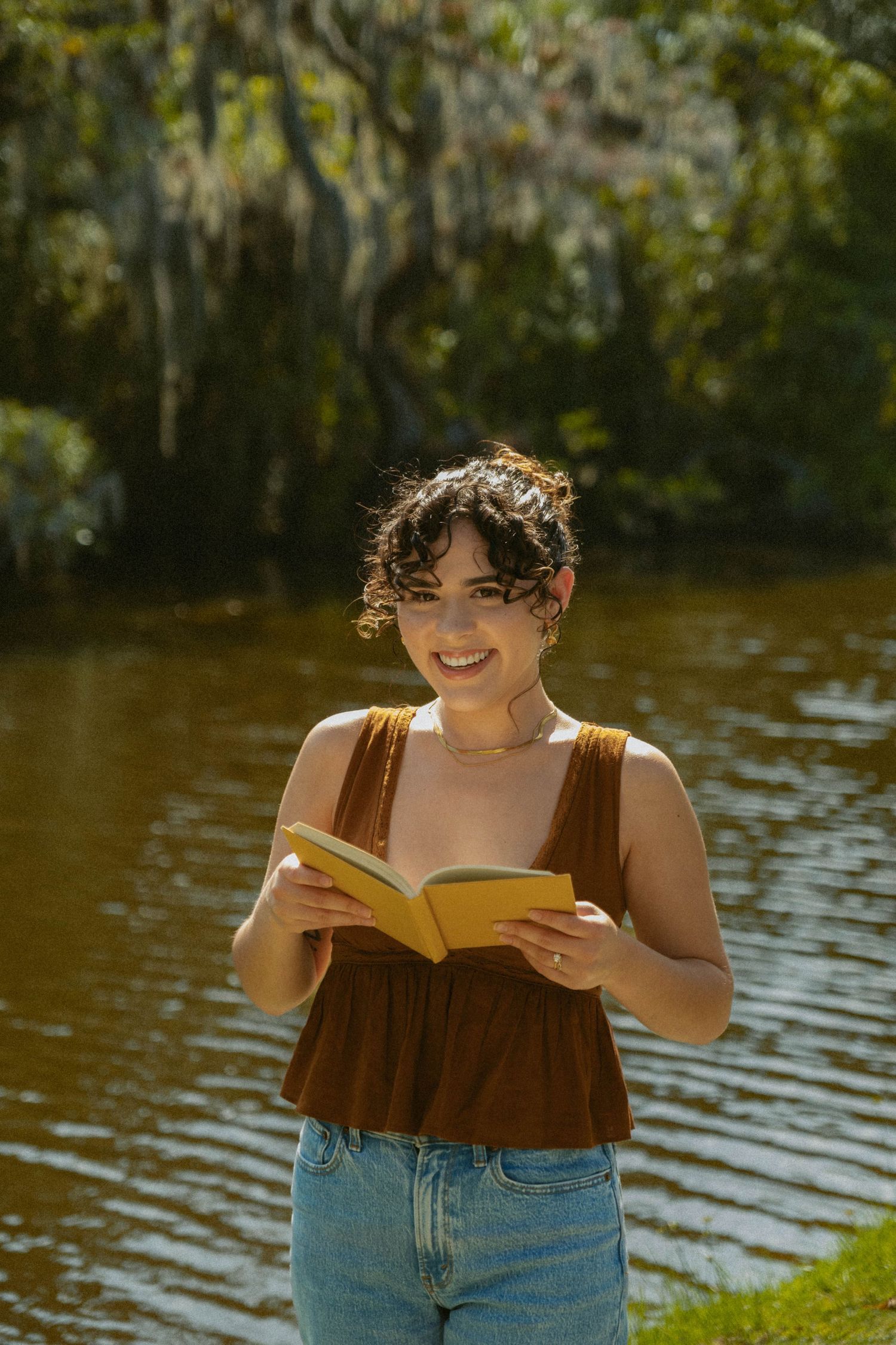 Person reading a book by a peaceful lakeside on a sunny afternoon.