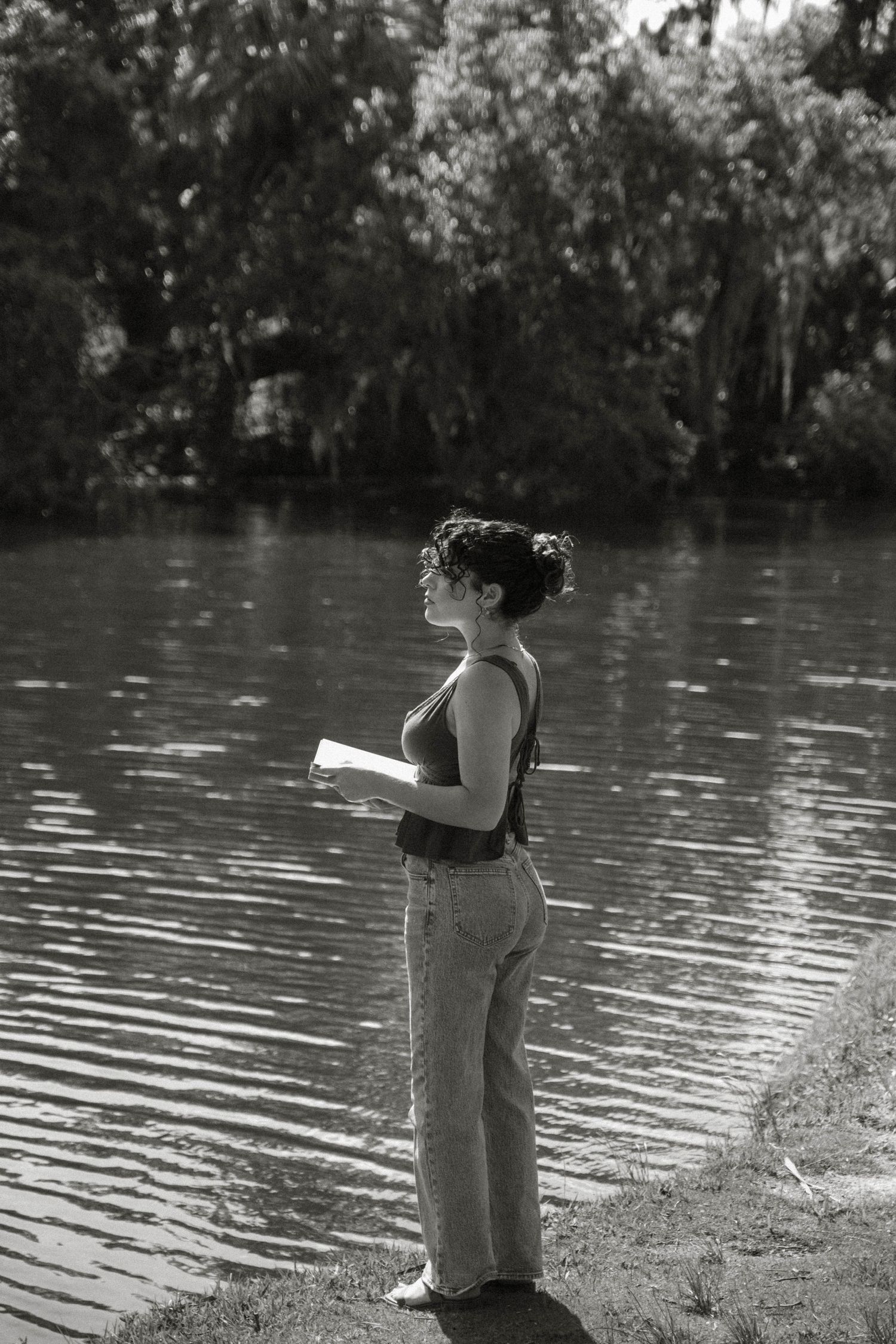 Figure standing by a serene lake in black and white photography.