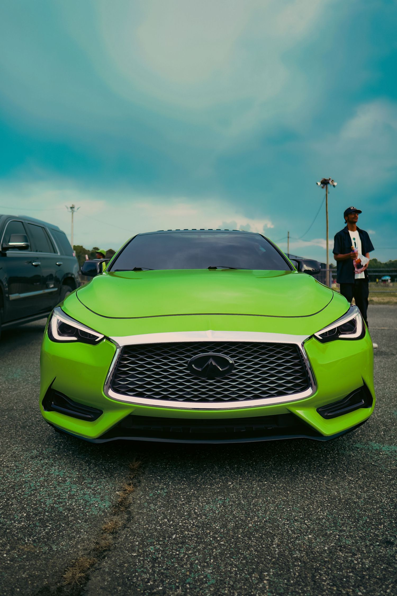 A bright lime green Infiniti Q60 sports car with aggressive front fascia and sleek LED headlights parked outdoors.
