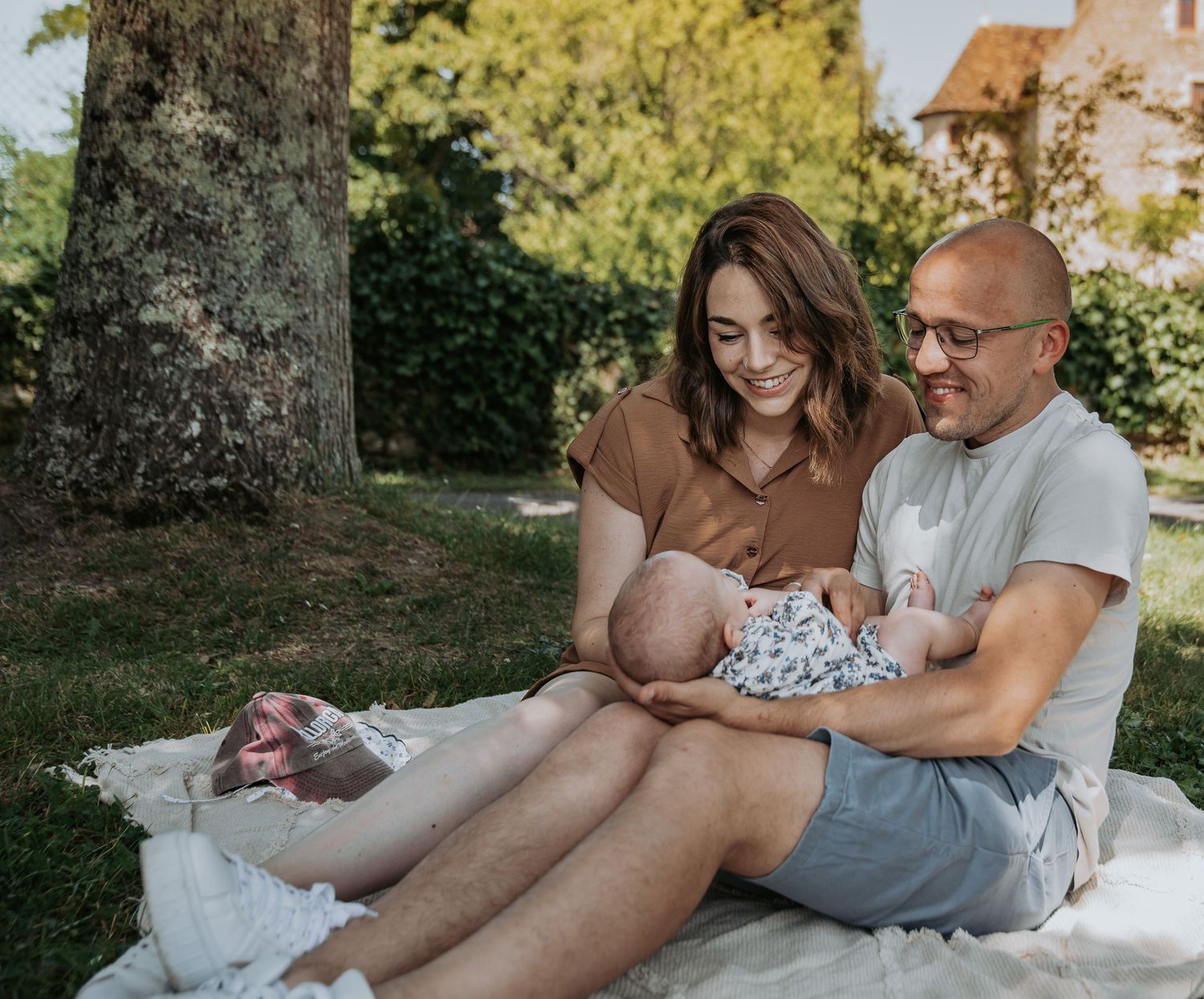 Family sitting on blanket in sunny garden while spending quality time together on warm summer day.