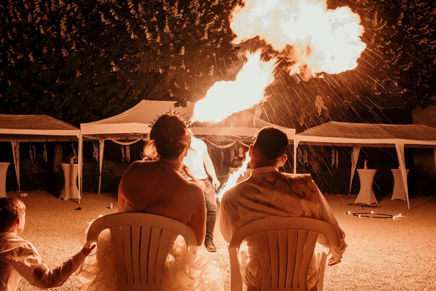 A sequence of fiery explosions and bright flashes illuminate a dark outdoor scene with lawn chairs.