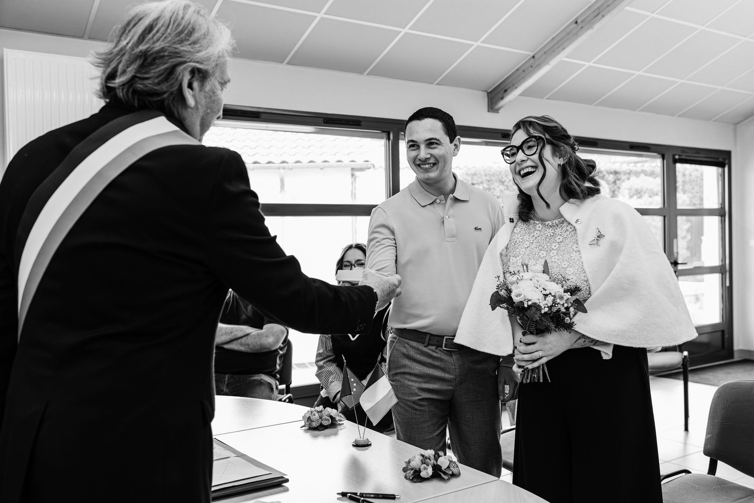 Black and white photo of a bride and groom shaking hands with an official at a civil wedding ceremony.