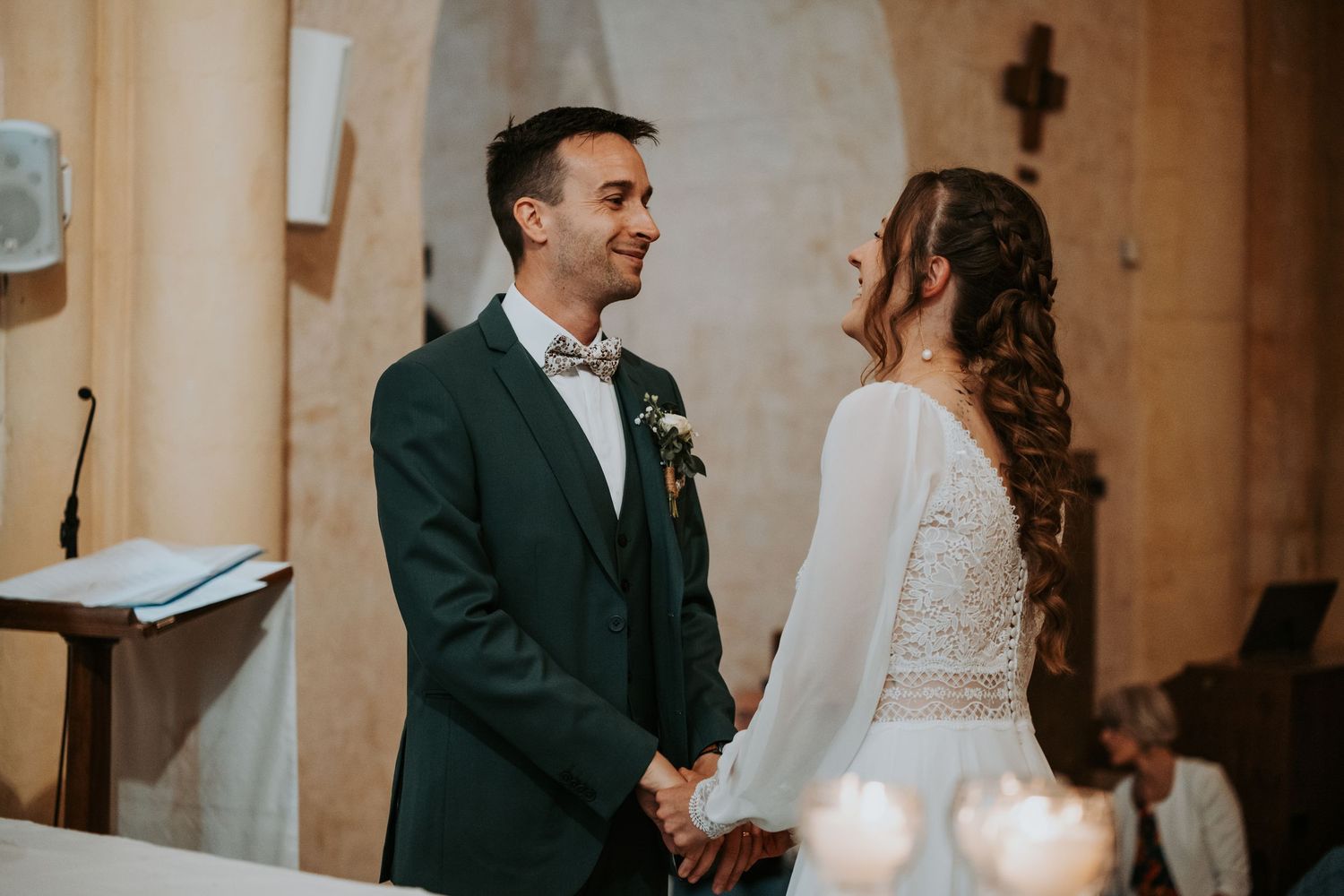 Bride and groom holding hands at church altar, smiling at each other during wedding ceremony.