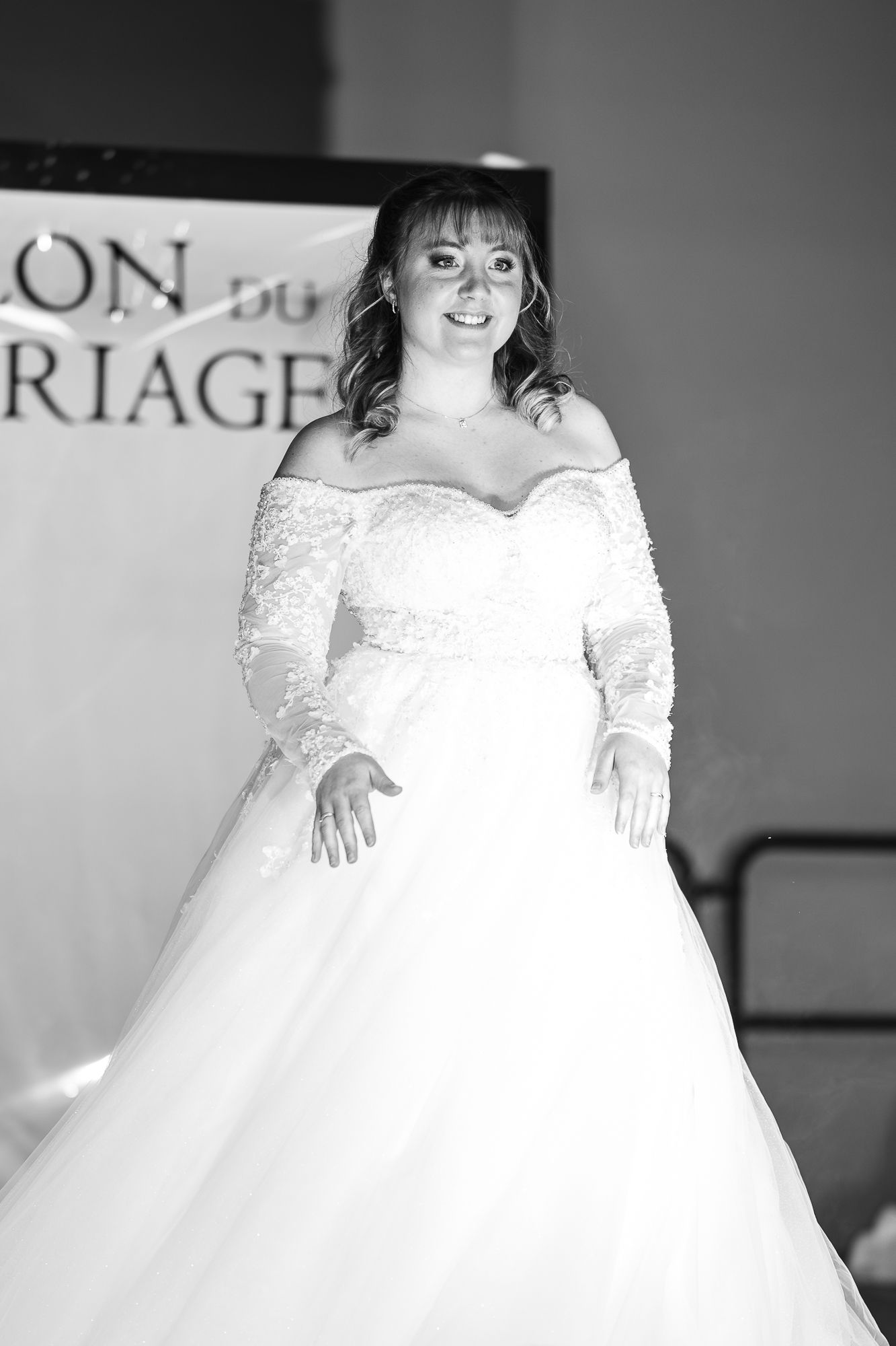 Wedding dress fashion show featuring flowing white ballgowns with lace details on a runway.