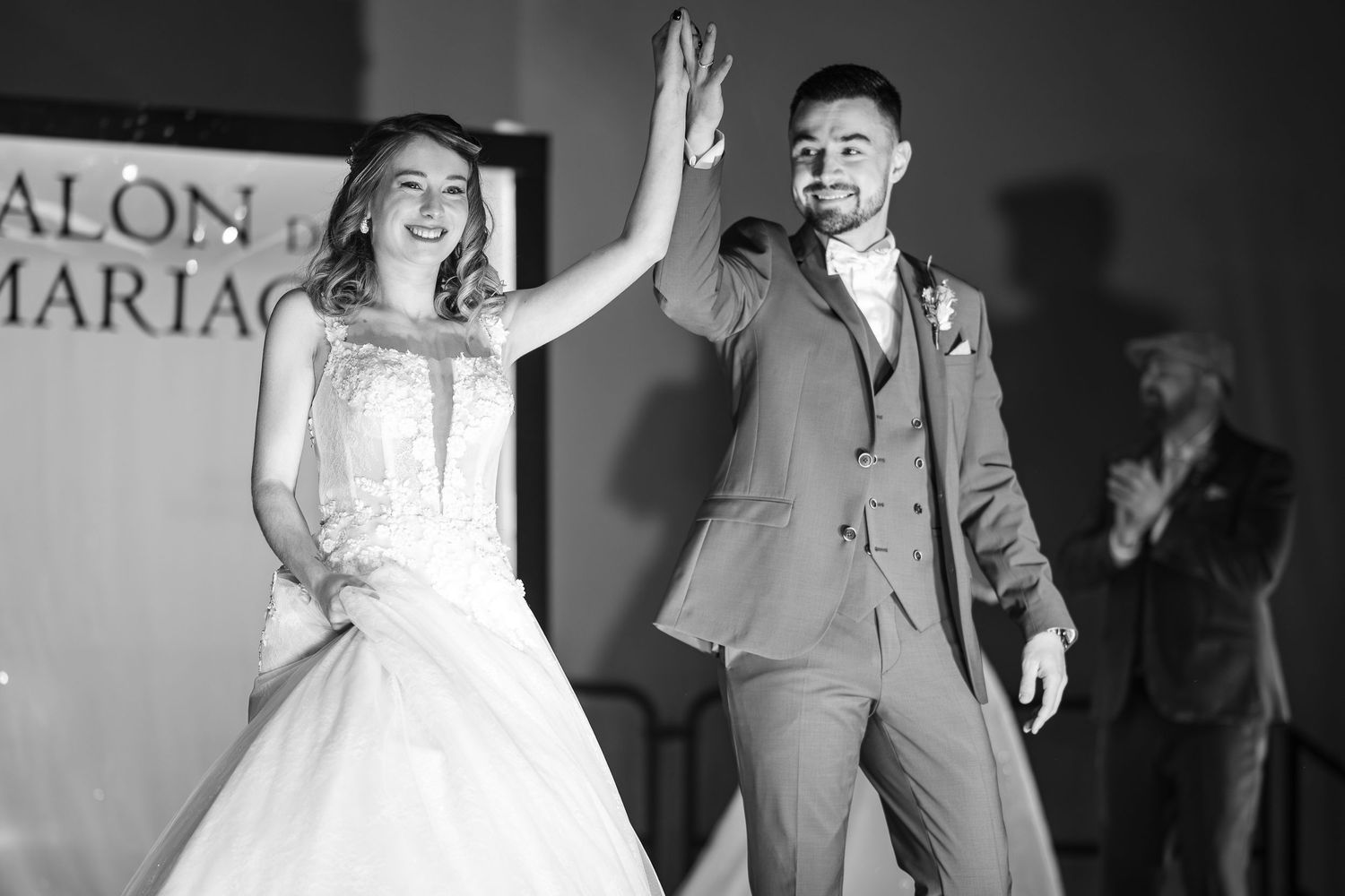 Bride and groom high-fiving joyfully at wedding reception in elegant black and white photo.