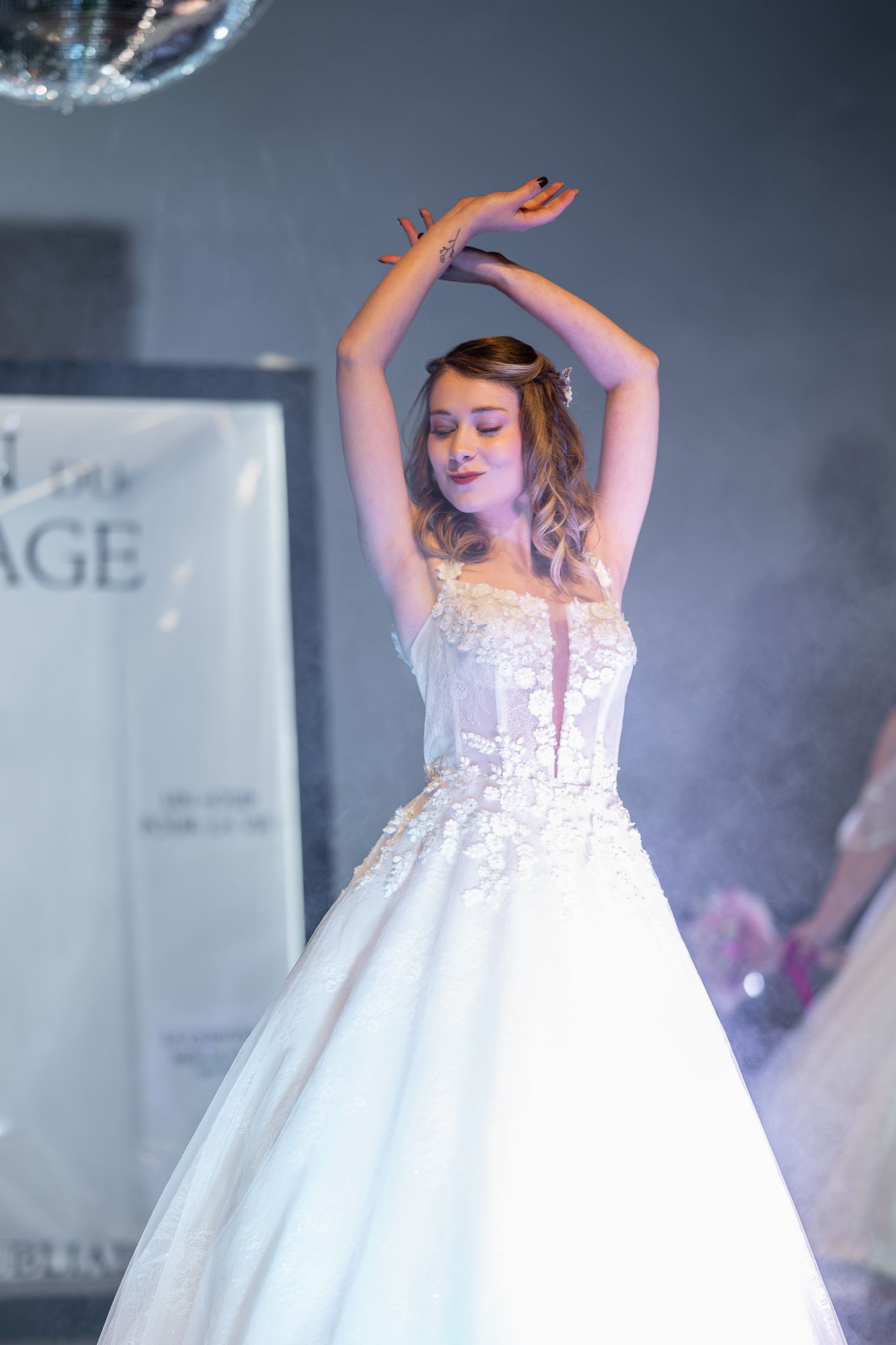 A young flower girl in a white dress twirls and dances under dramatic stage lighting.