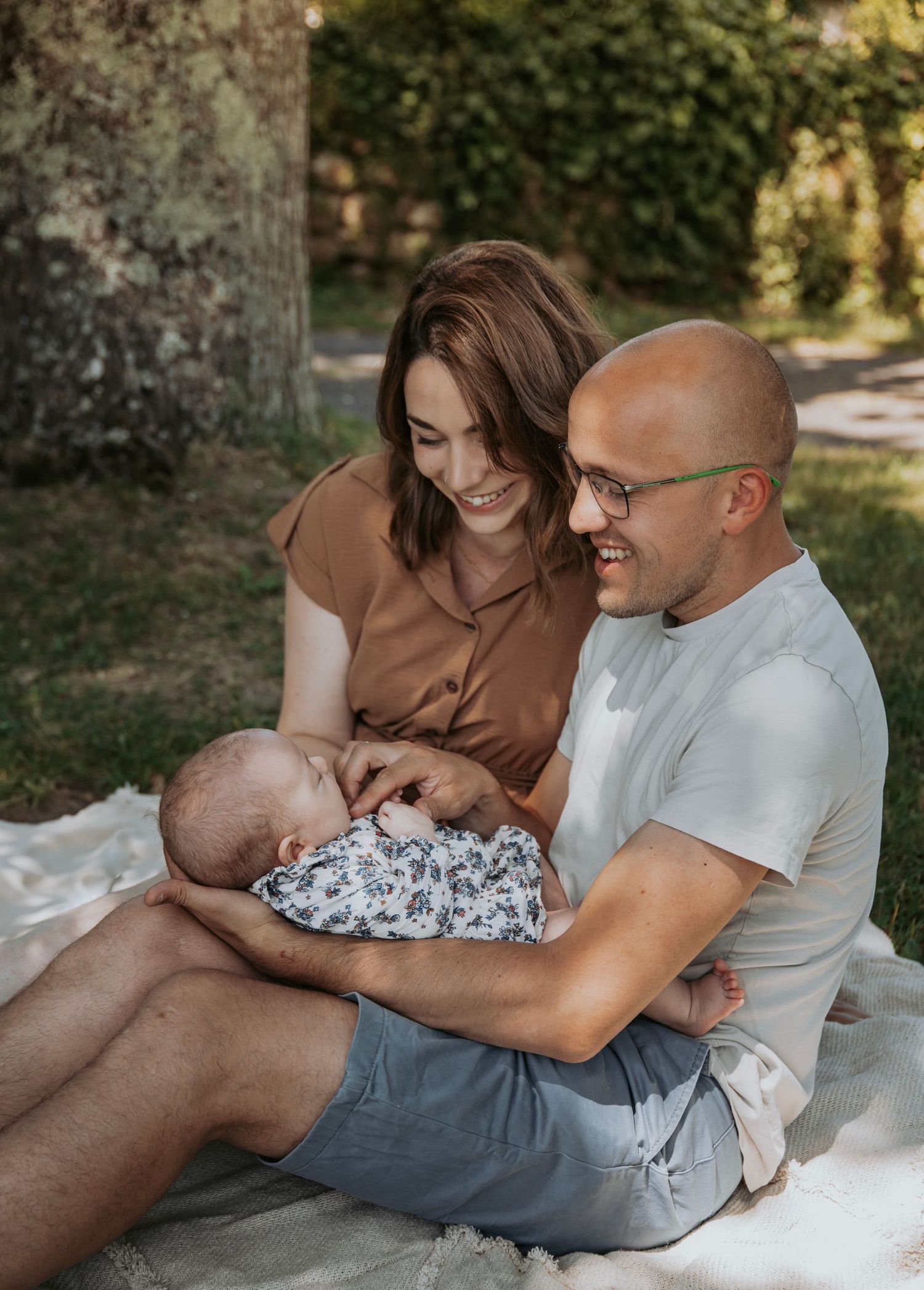 A couple lounges on white blankets outdoors for intimate lifestyle photography in natural light.