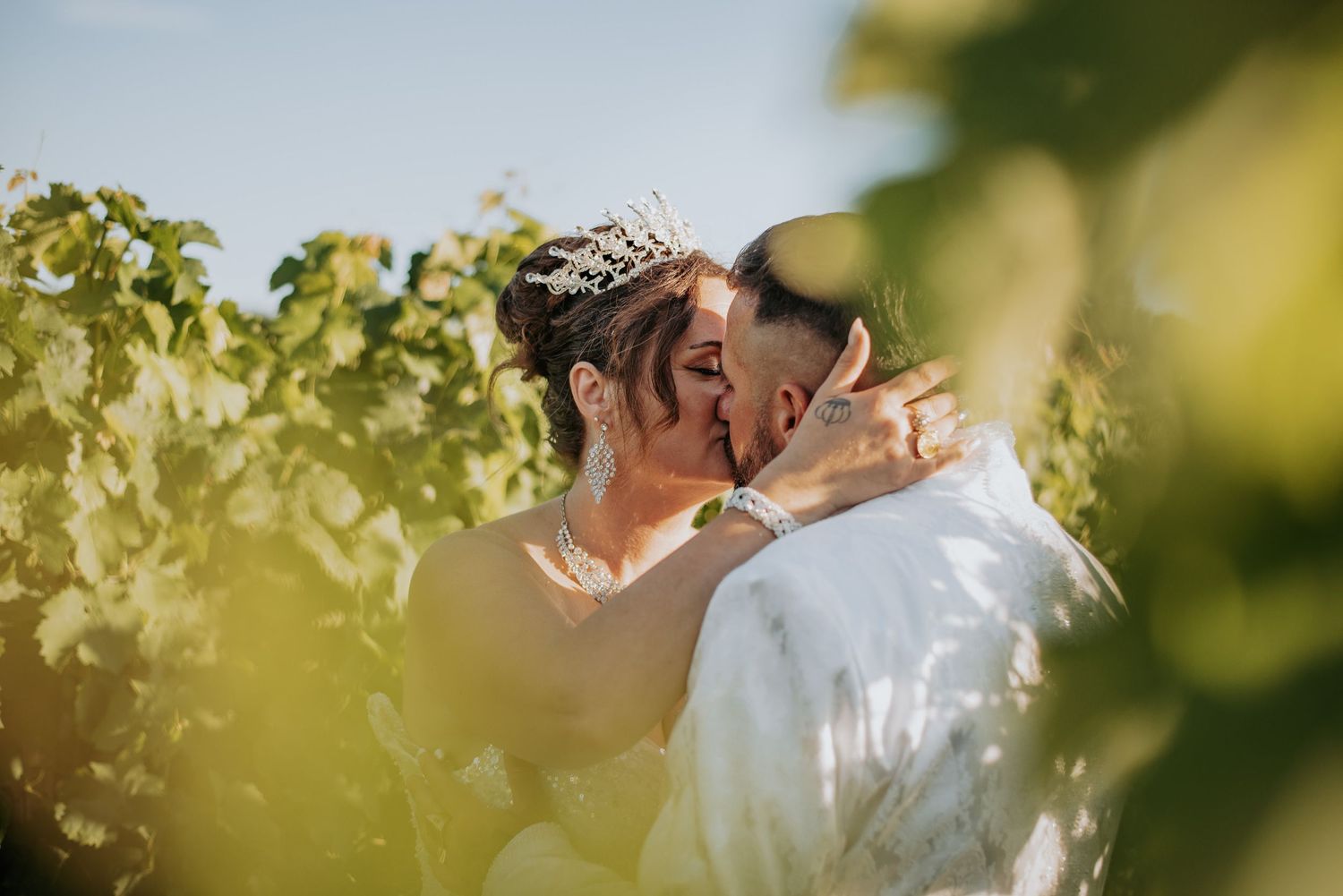 Elegant wedding couple embraces in a sun-dappled garden setting with soft bokeh lighting effects.