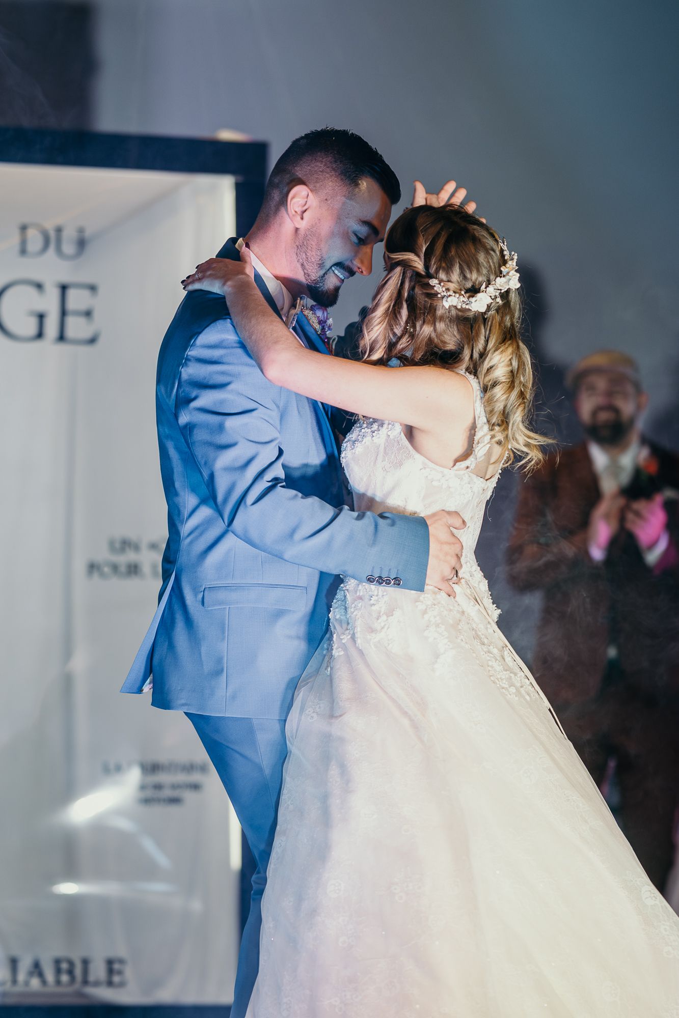 A couple shares their first dance at their wedding reception, with the bride in white and groom in light blue suit.