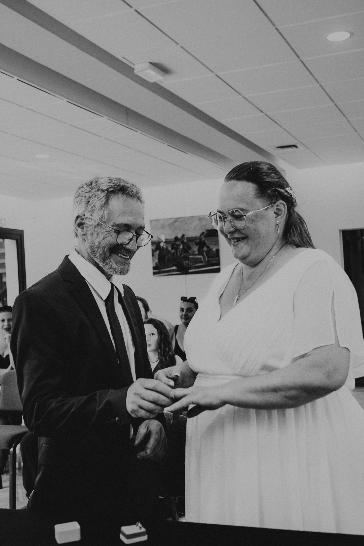 Black and white photo showing people in formal attire having a conversation in an office hallway.