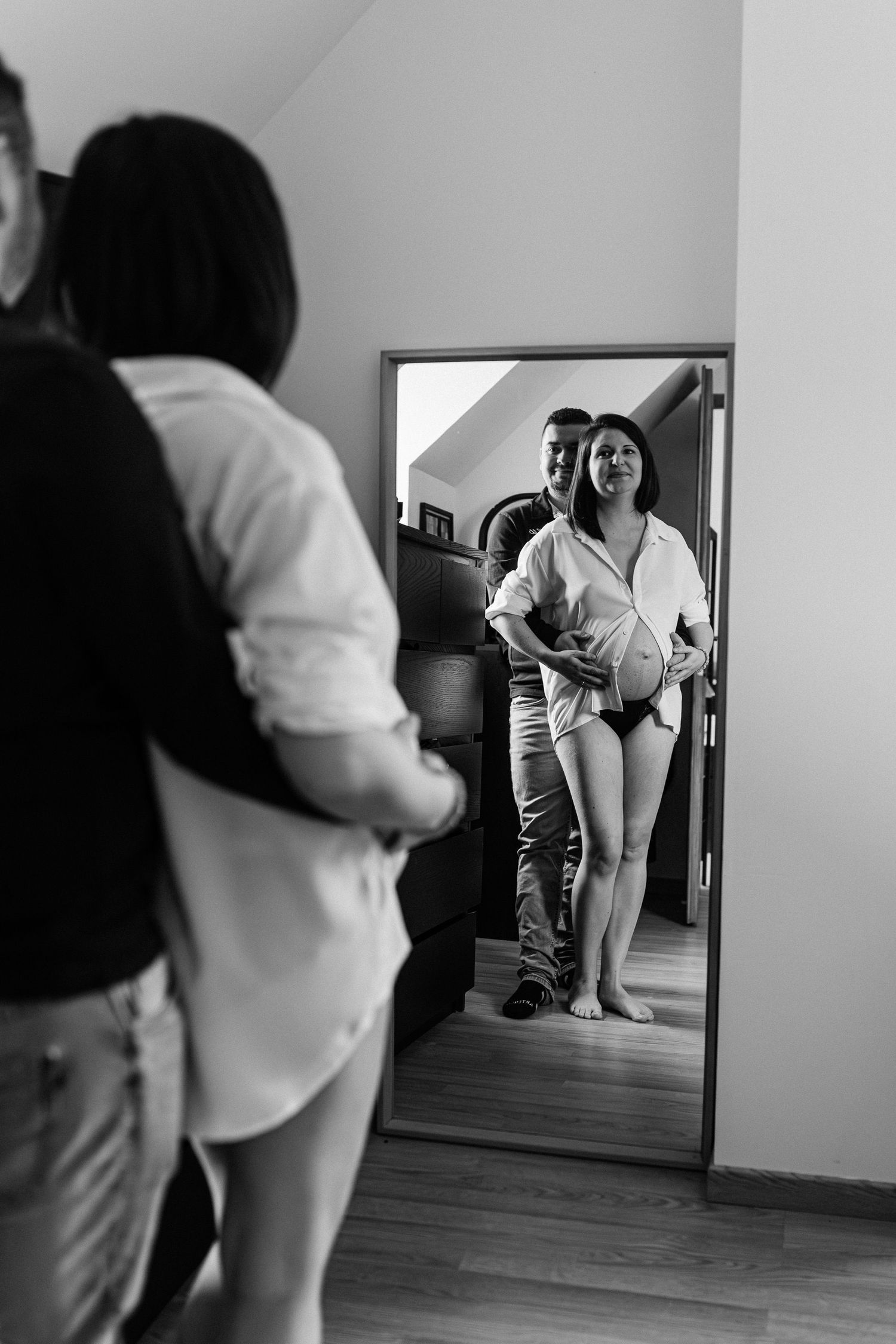 Black and white mirror reflection images showing a person sitting on the floor in a minimalist interior setting.