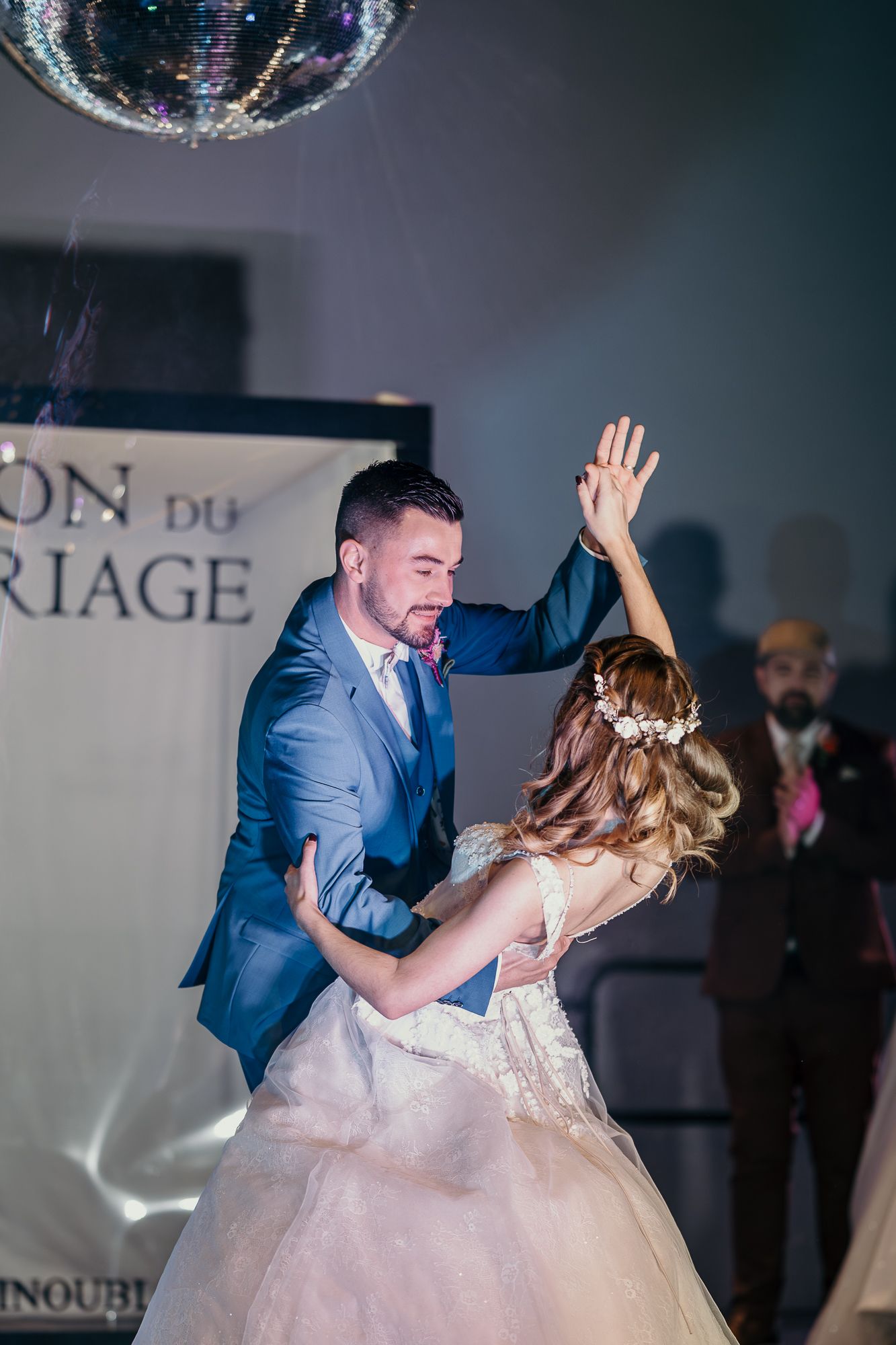 Couple dancing under a disco ball at their wedding reception with dramatic lighting effects.