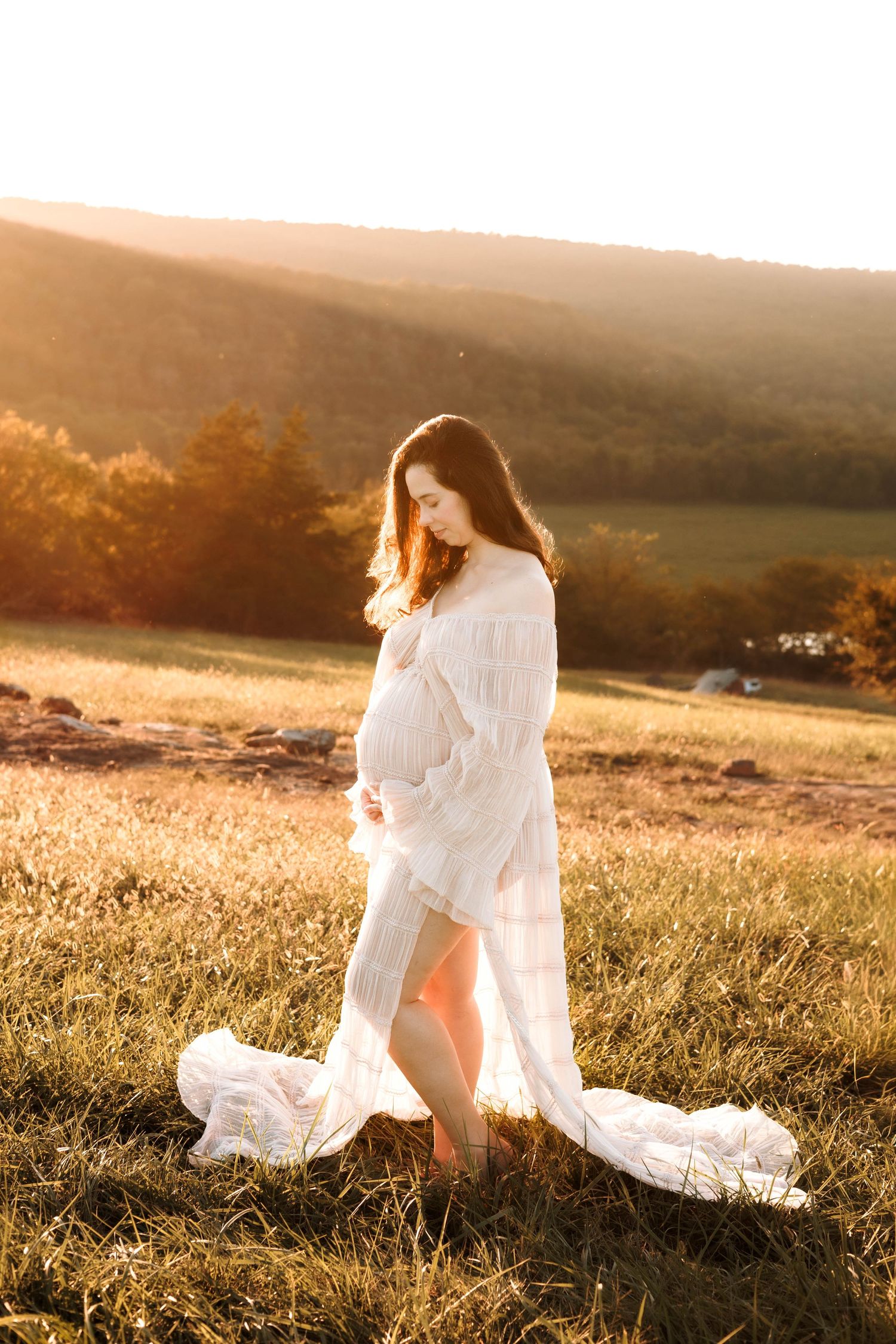 Ethereal figure in flowing white dress dances through golden sunlit meadow at sunset creating dreamy silhouette.