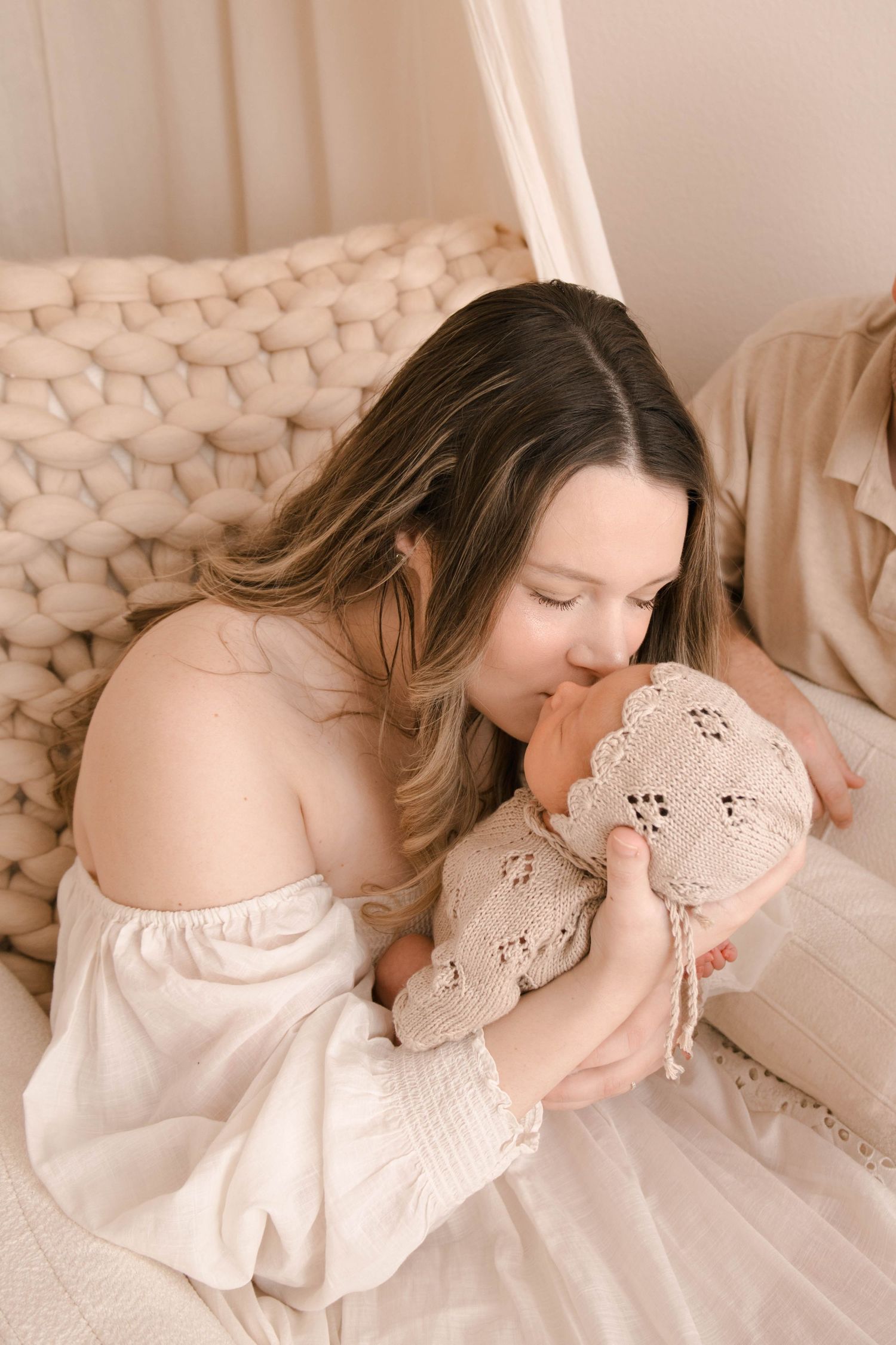 Tender moment captured in soft natural light with cream and neutral tones.